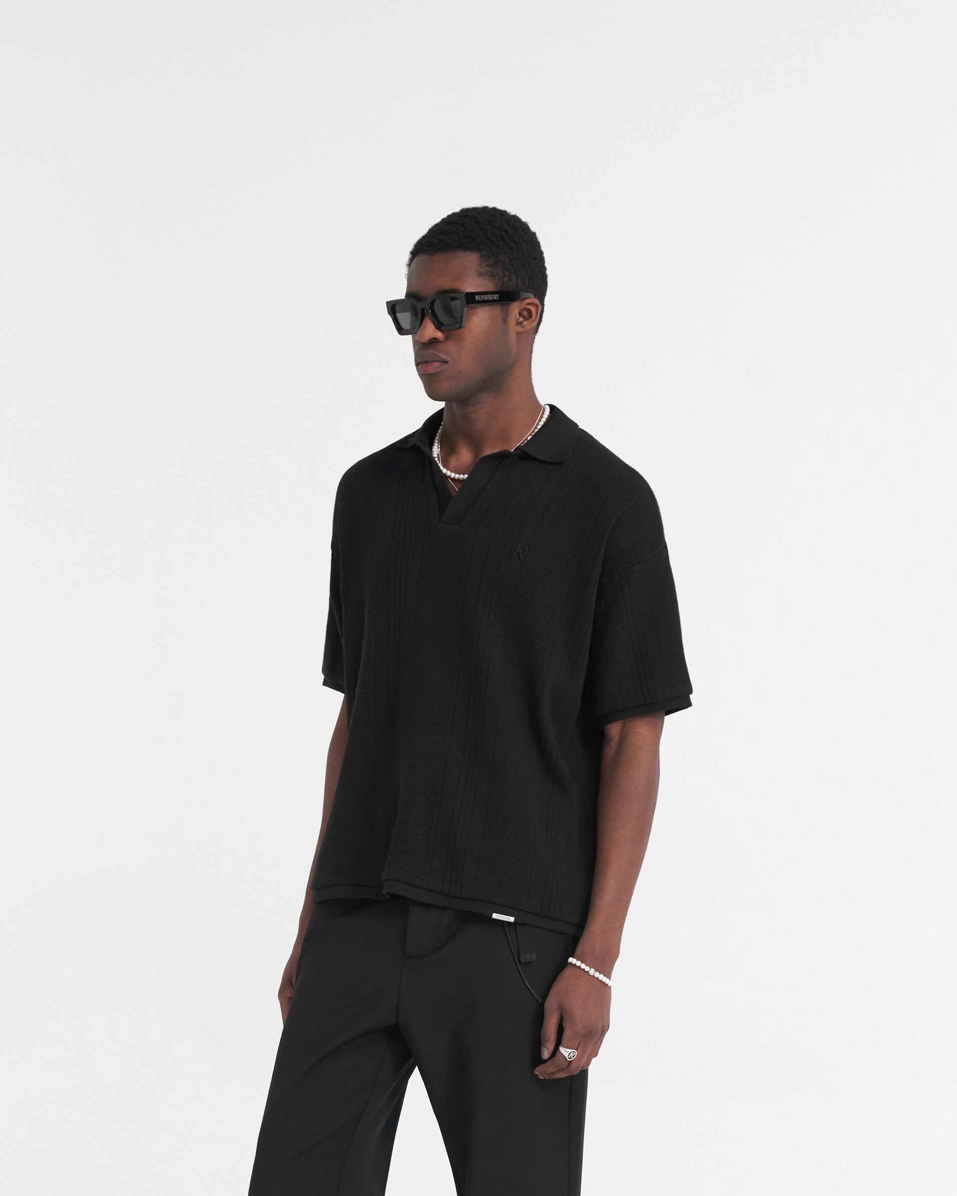 Back product image of a mens black polo shirt on a plain white background | Open Stitch Polo in Black | Polo shirt with open collar and embroidered logo | SS24 T-Shirts | Represent Clo