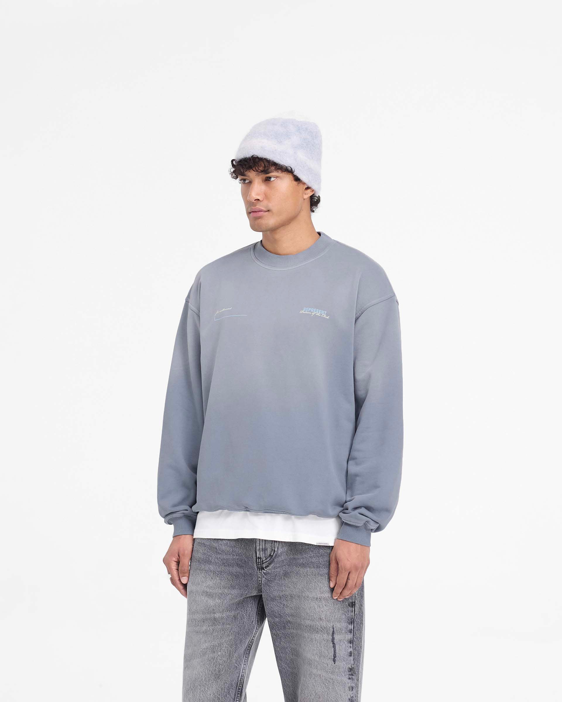 Man wearing a grey oversized sweater on a plain white background | Patron Of The Club Sweater in Washed Grey | Oversized heavyweight jersey sweater with Patron of the Club print | Patrons Sweaters | Represent Clo