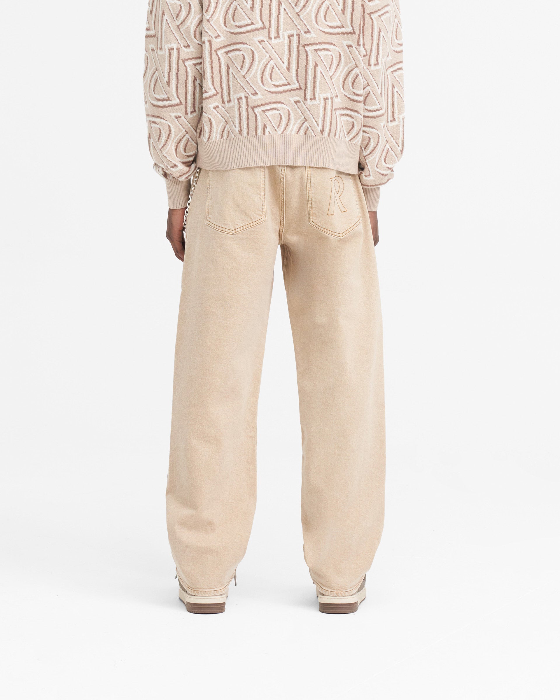 Man wearing baggy denim jeans in dirt cashmere on a plain white background | R3 Baggy Denim in Dirt Cashmere | Relaxed fit denim jeans with heavy wash | SS24 Denim | Represent Clo