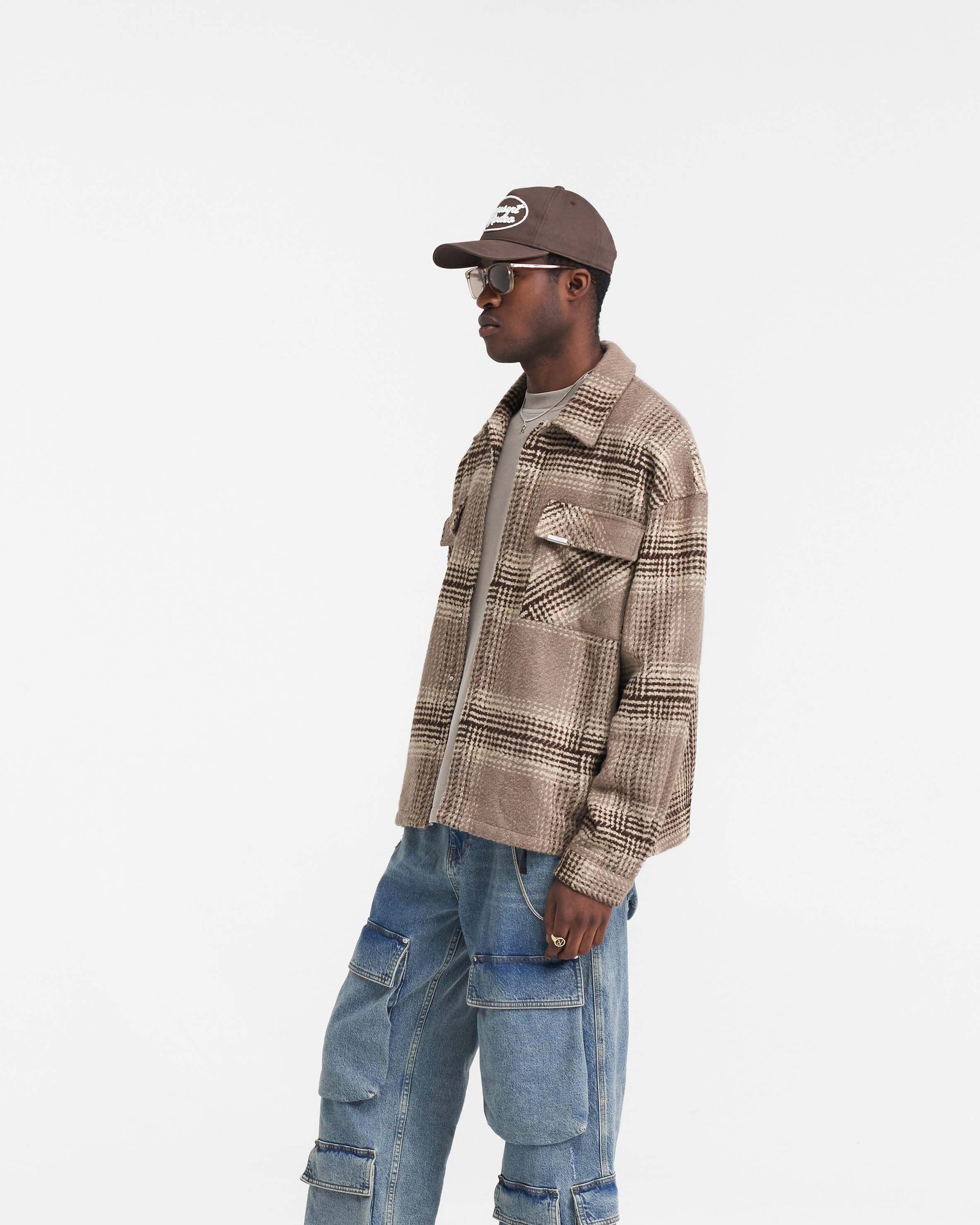 Man wearing a brown check overshirt on a plain white background | Represent Flannel Shirt in Brown Check | Flannel shirt with chest patch pockets | FW24 Shirts | Represent Clo