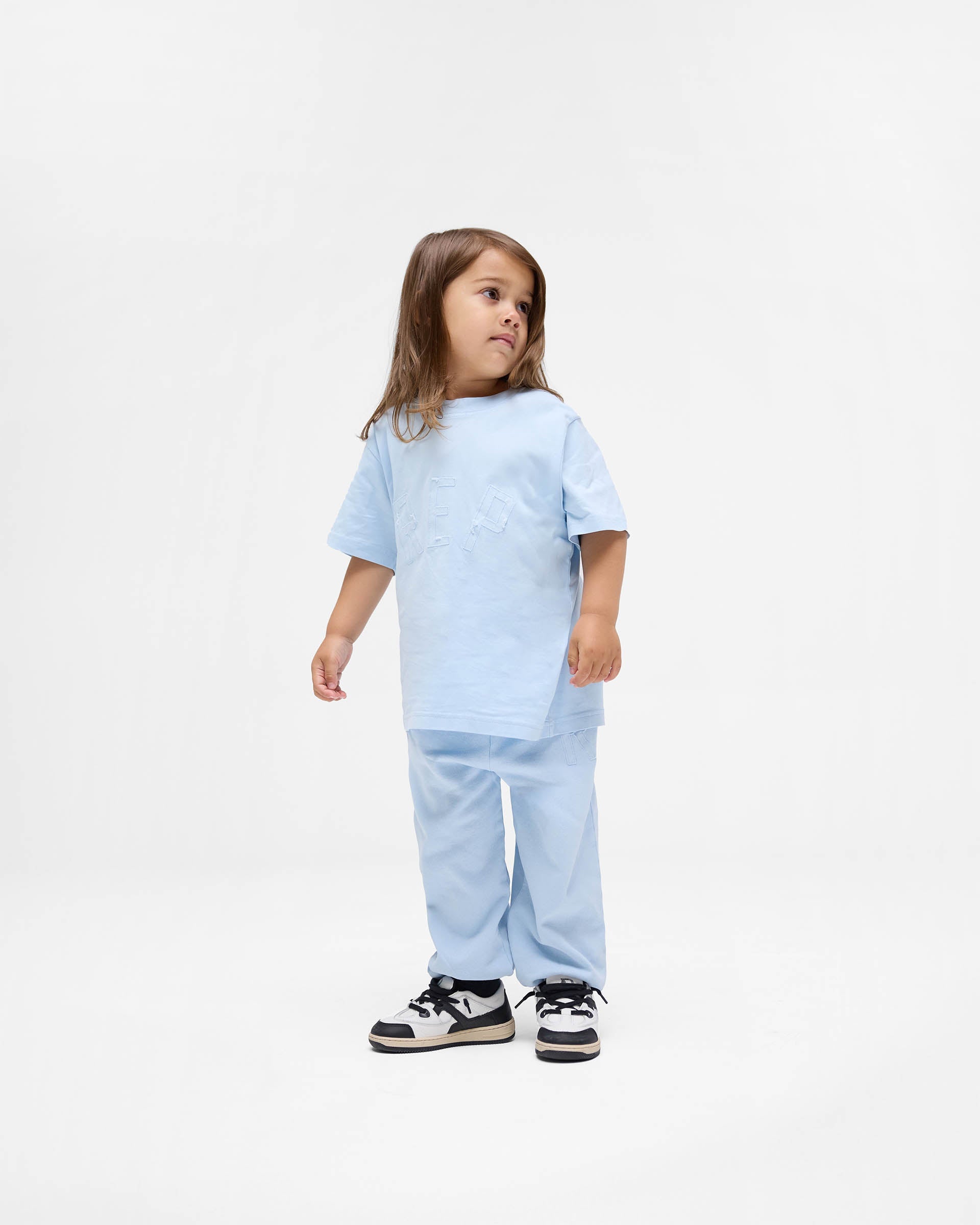 Back product image of kids powder blue sweatpants on a plain white background | Mini Rep Applique Sweatpants in Powder Blue | Sweatpants with elasticated waistband and cuffs | FW24 Pants | Represent Clo