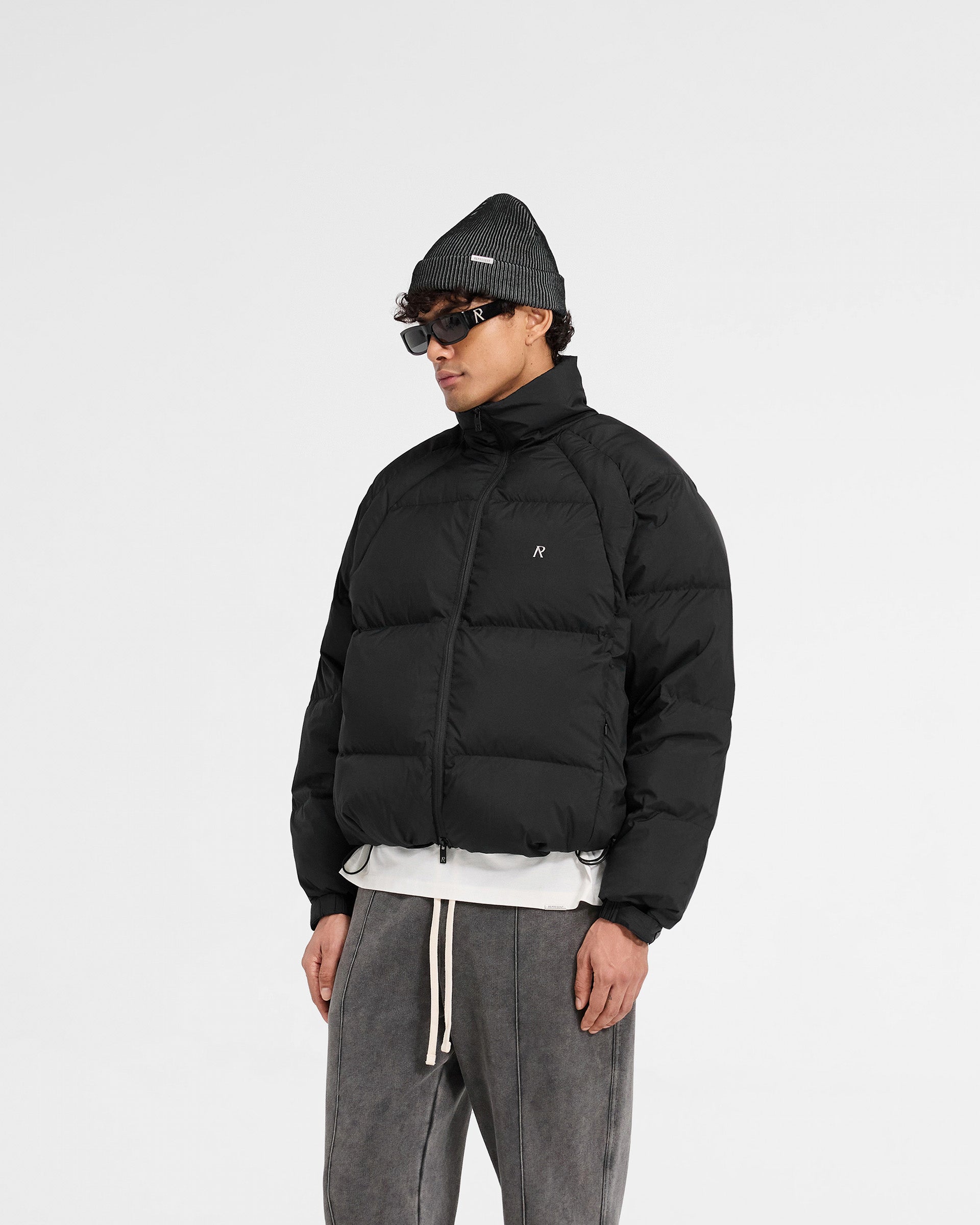Back product image of a mens black puffer jacket on a plain white background | Funnel Neck Puffer in Black | Puffer with raglan sleeves and toggle hem adjustment | PRE SS25 Outerwear | Represent Clo