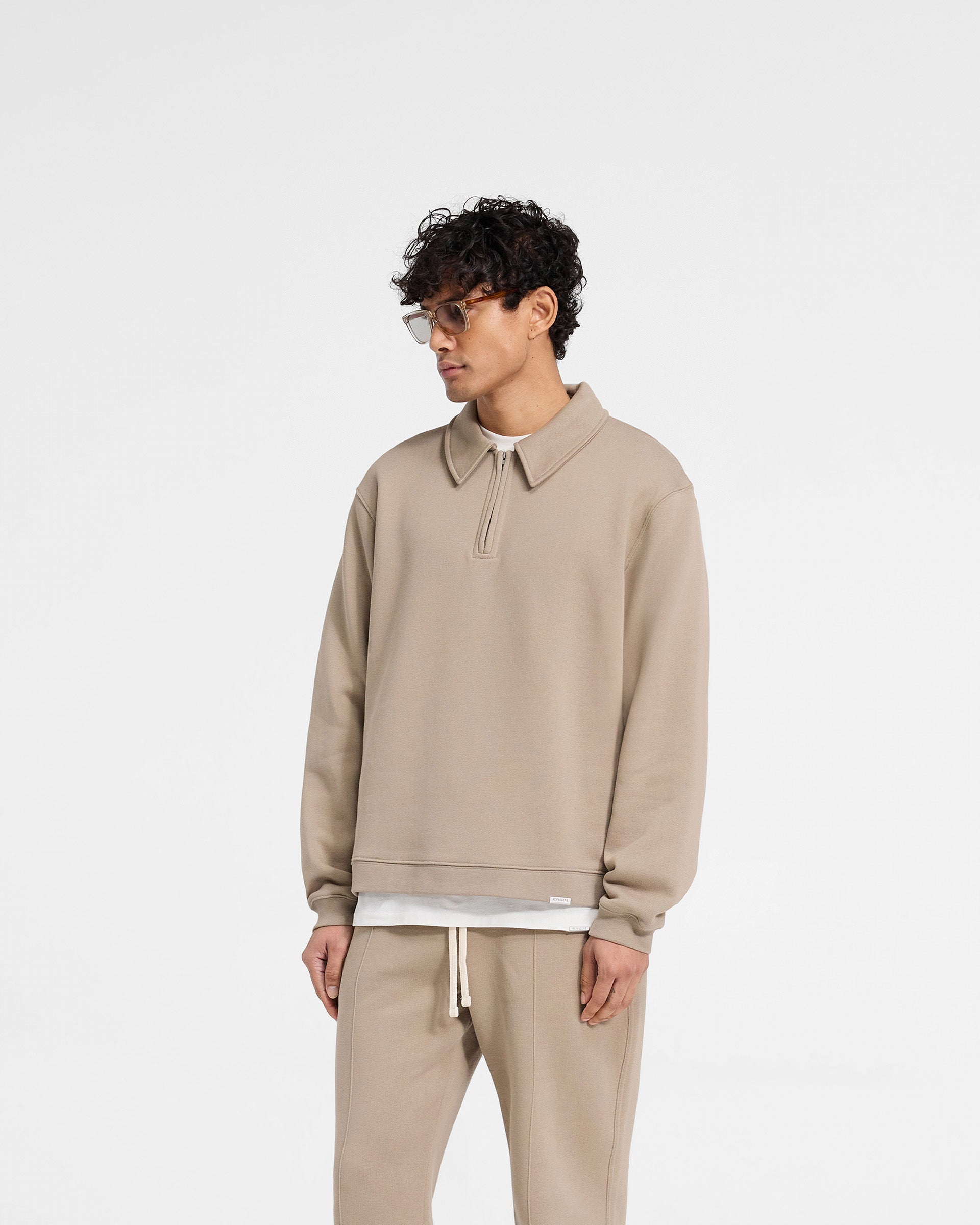 Back product image of a mens beige quarter zip on a plain white background | Initial Boxy Quarter Zip in Dune | Oversized boxy fit sweater with RiRi zip and embroidered details | Initial Sweaters | Represent Clo
