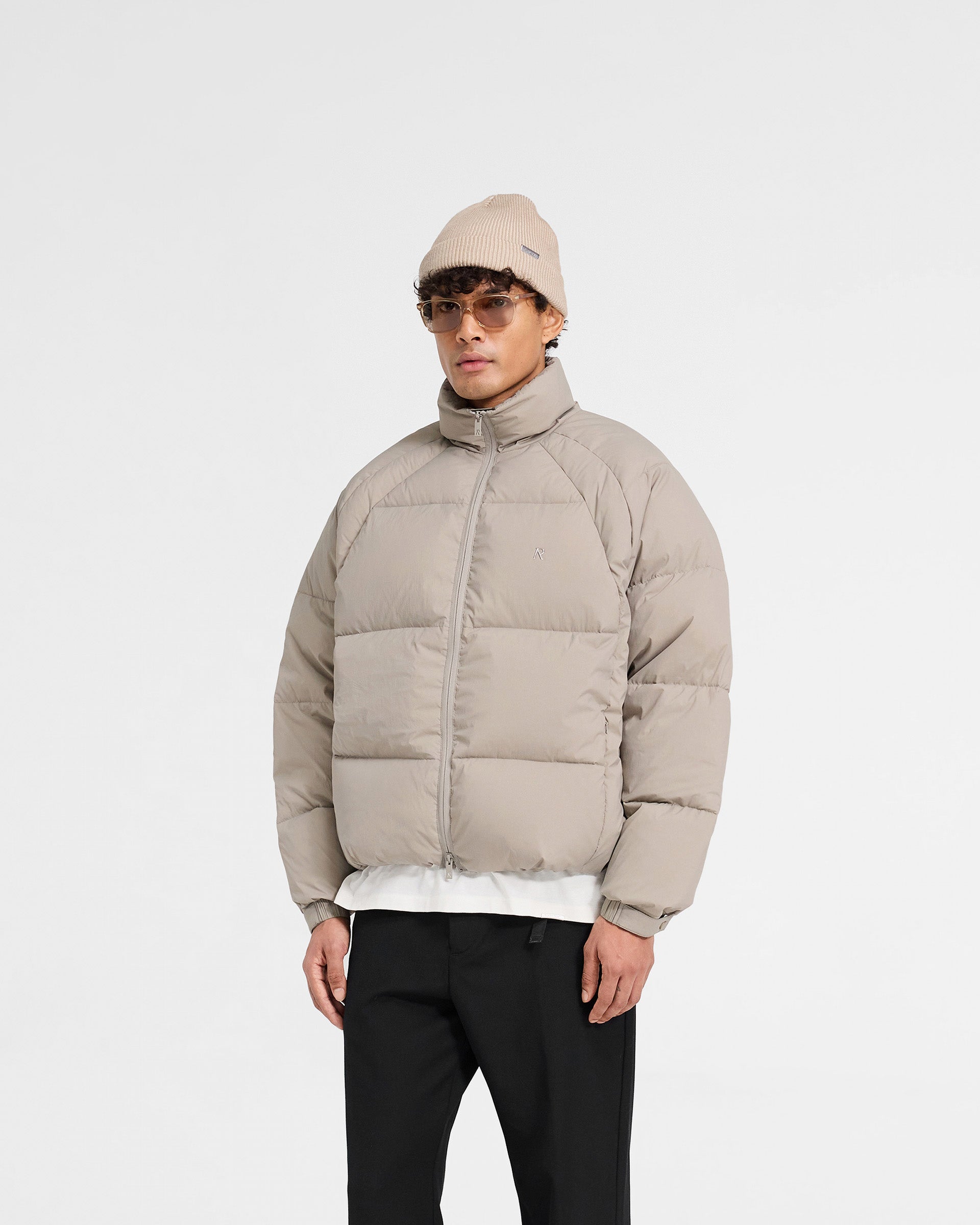 Back product image of a mens dune puffer jacket on a plain white background | Funnel Neck Puffer in Dune | Puffer jacket with baffles and toggle hem | PRE SS25 Outerwear | Represent Clo
