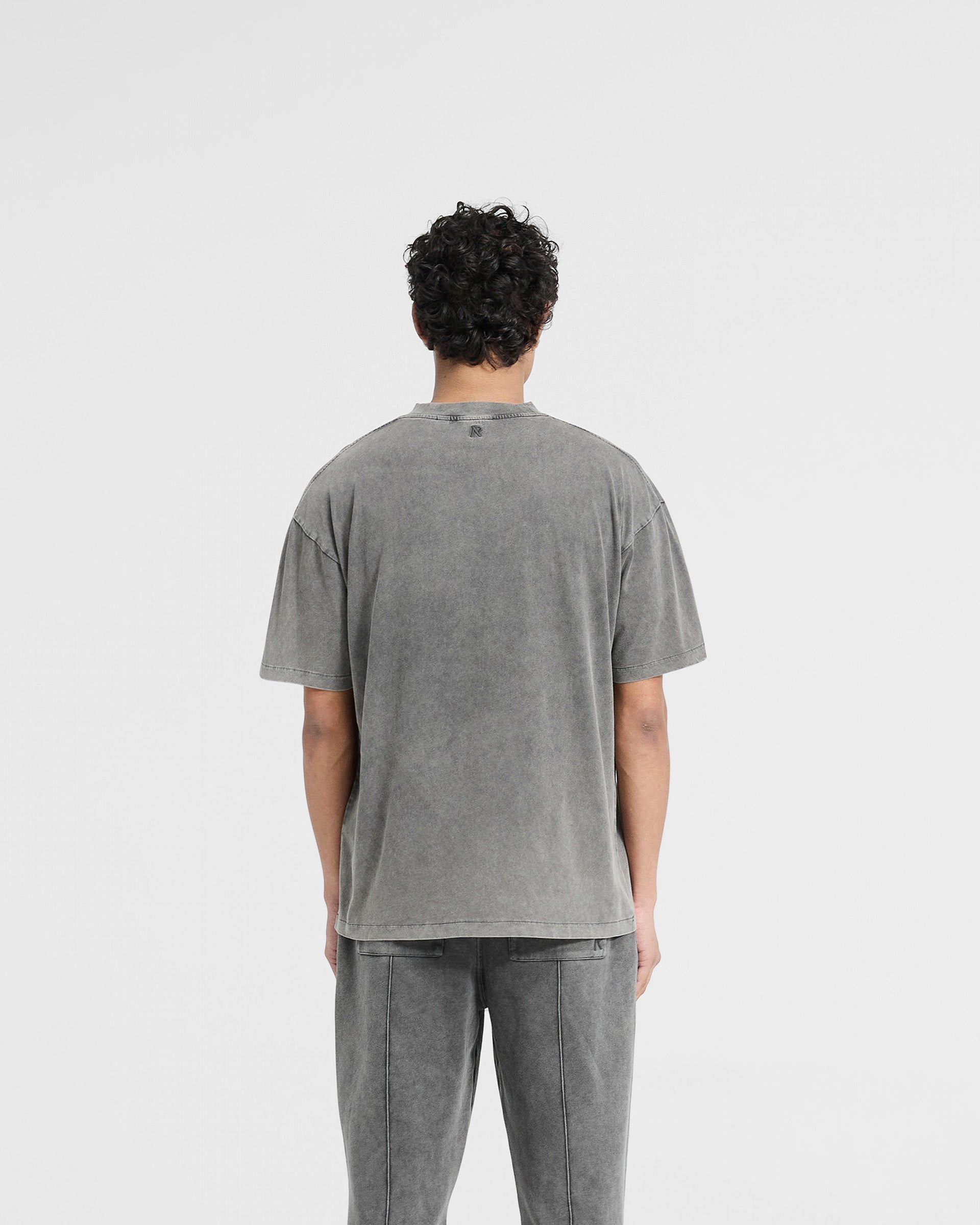 Man wearing an oversized grey t-shirt on a plain white background | Initial Oversized T-Shirt in Vintage Grey | T-shirt with embroidered initial and metal bar | Initial T-Shirts | Represent Clo
