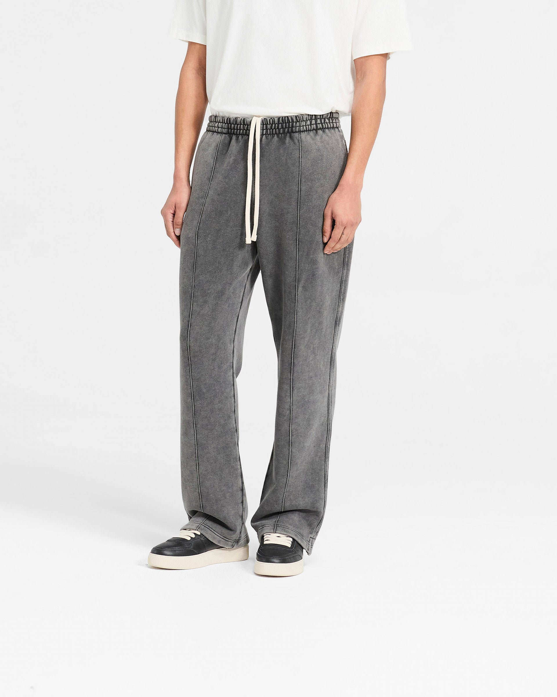 Man wearing vintage grey sweatpants on a plain white background | Initial Sweatpants in Vintage Grey | Wide leg sweatpants with pintuck detail and elasticated waistband | Initial Pants | Represent Clo