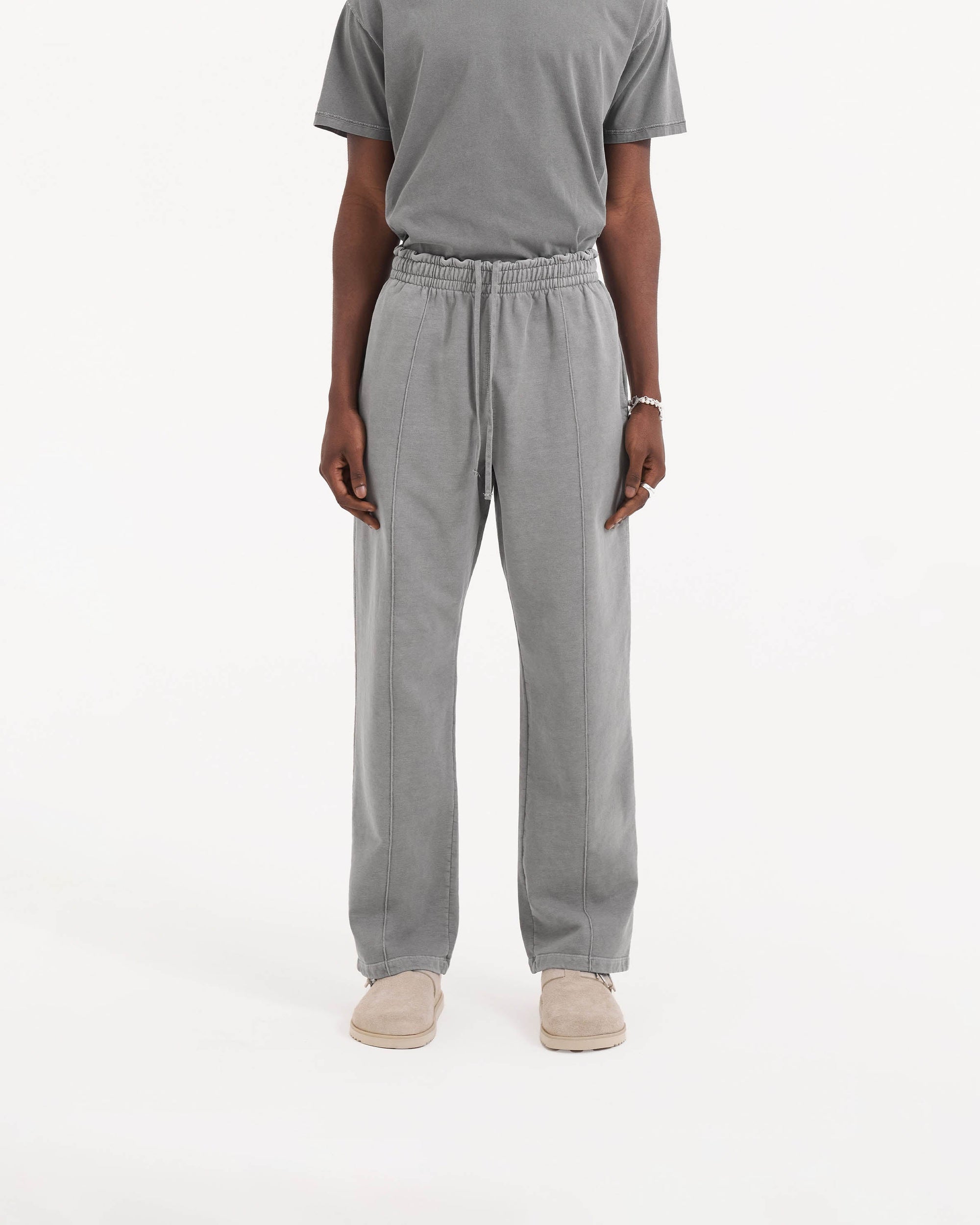 Man wearing grey wide leg sweatpants on a plain white background | Initial Sweatpant in Ultimate Grey | Sweatpants with elasticated waistband and pintuck detail | Initial Pants | Represent Clo