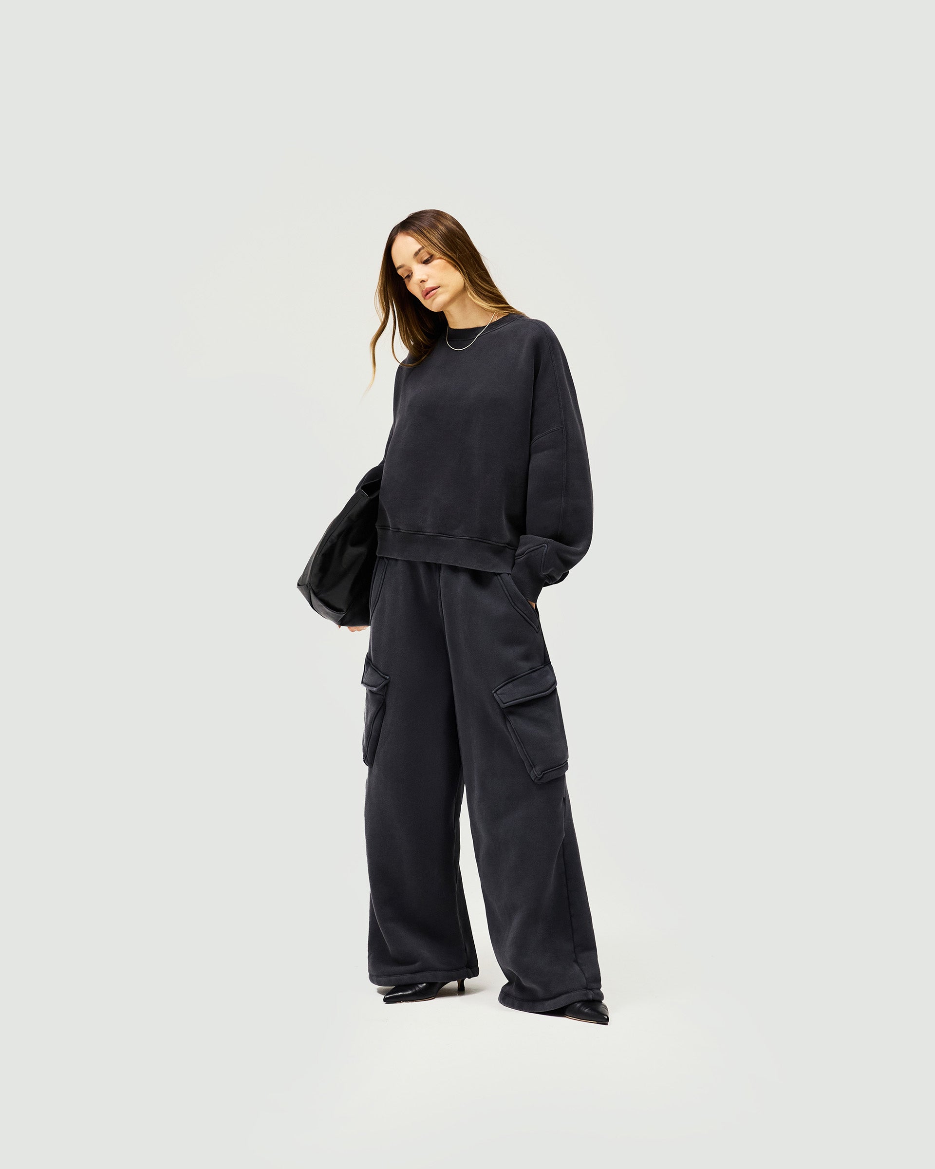 Woman wearing a black V notch sweater on a plain white background | Initial V Notch Sweater in Washed Black | Heavyweight cotton sweater with a relaxed fit | Womens Initial Sweaters | Represent Clo