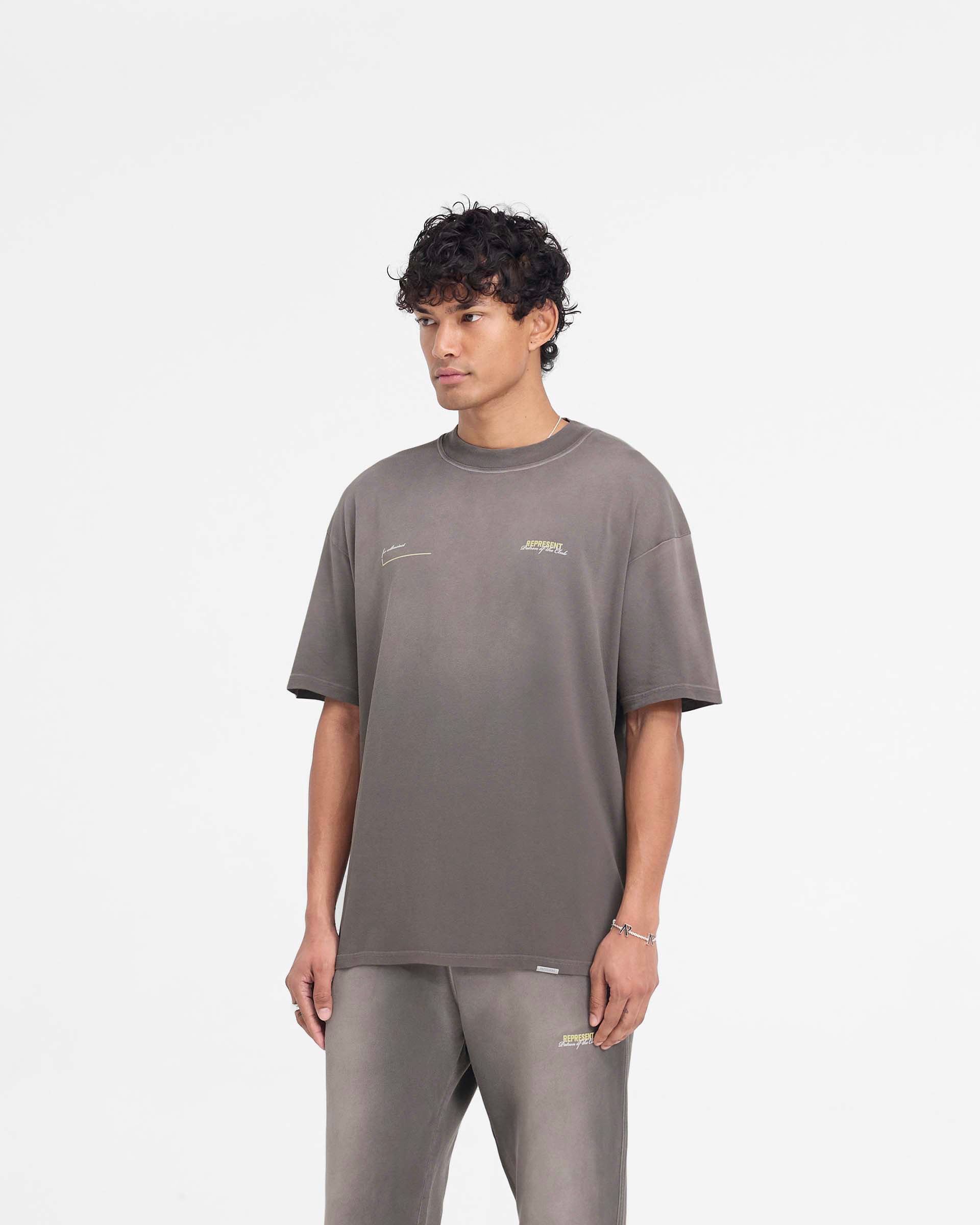 Man wearing a slightly oversized olive t-shirt on a plain white background | Patron Of The Club T-Shirt in Washed Olive | Olive t-shirt with fade out wash and ribbed crewneck | Patrons T-Shirts | Represent Clo