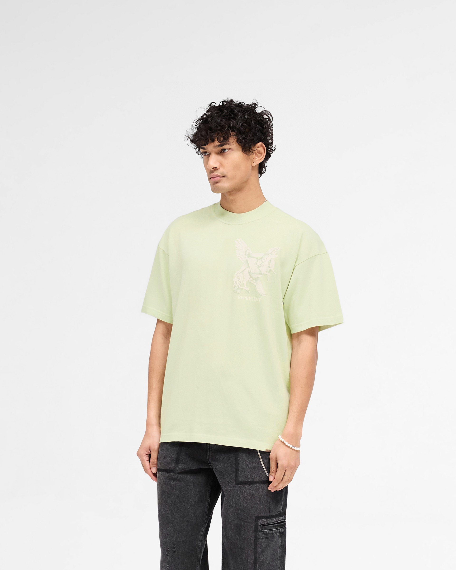 Man wearing a green t-shirt on a plain white background | Elegance In Motion T-Shirt in Matcha | Slightly oversized t-shirt with graphic and metal bar logo | SS25 T-Shirts | Represent Clo