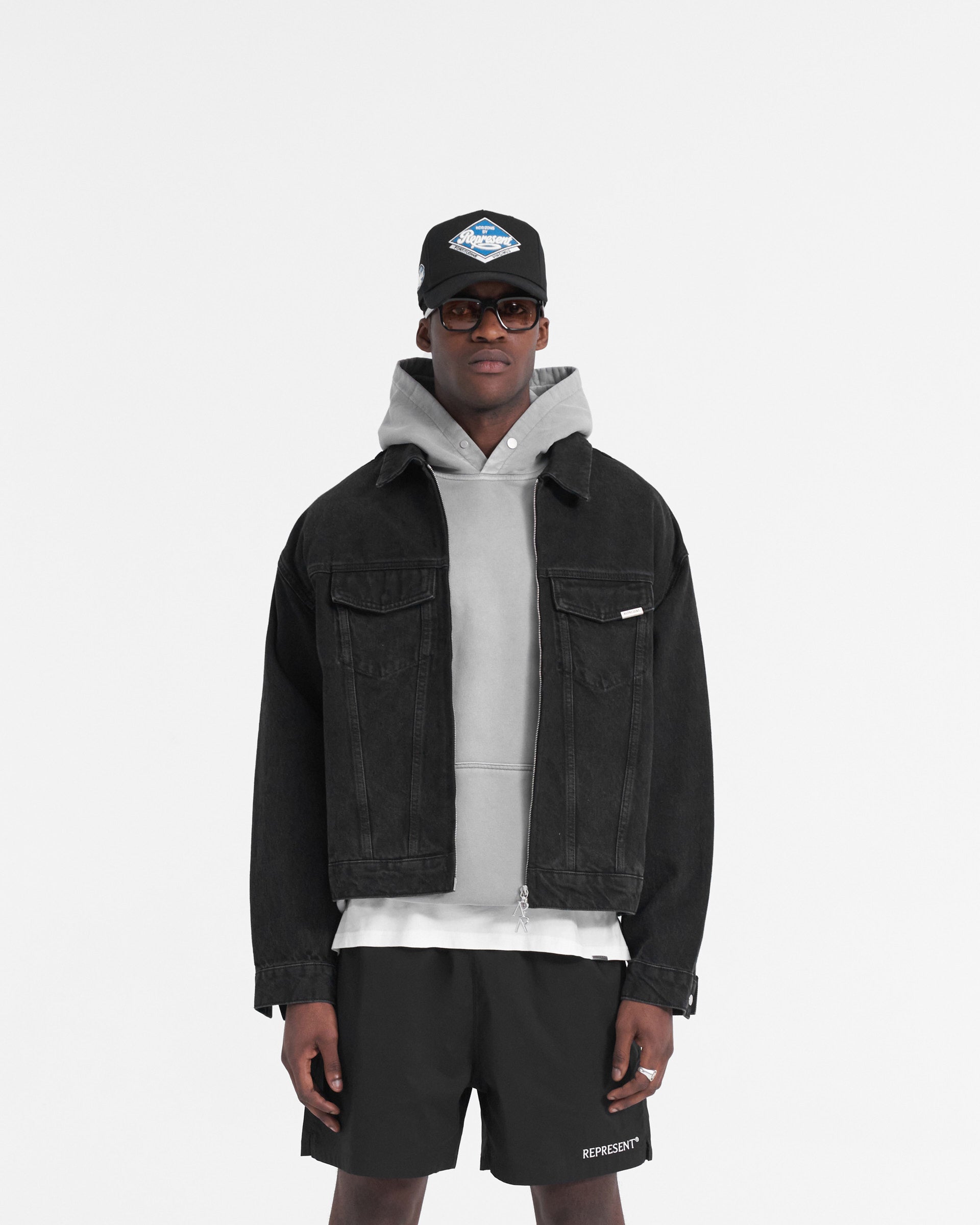 Man wearing a black denim jacket on a plain white background | R4 Denim Jacket in Black | Slightly oversized denim jacket with heavy wash and zip closure | SS24 Denim | Represent Clo