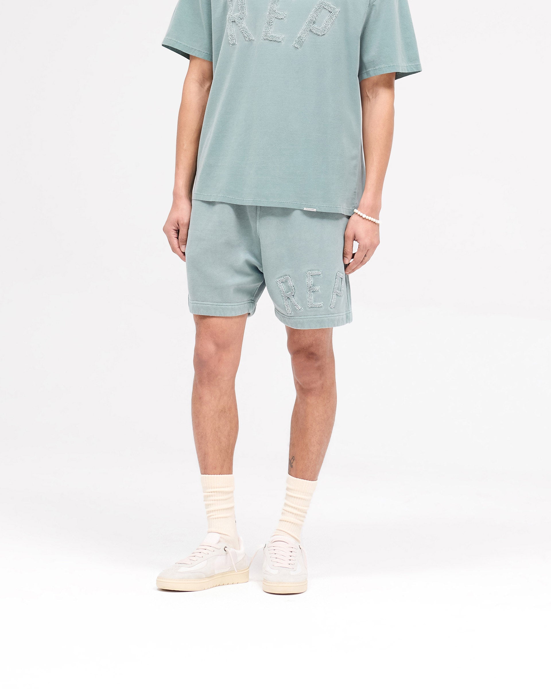 Back product image of mens green shorts on a plain white background | Rep Applique Shorts in Forest Green | Boxy fit shorts with back pockets and applique logo | SS25 Shorts | Represent Clo