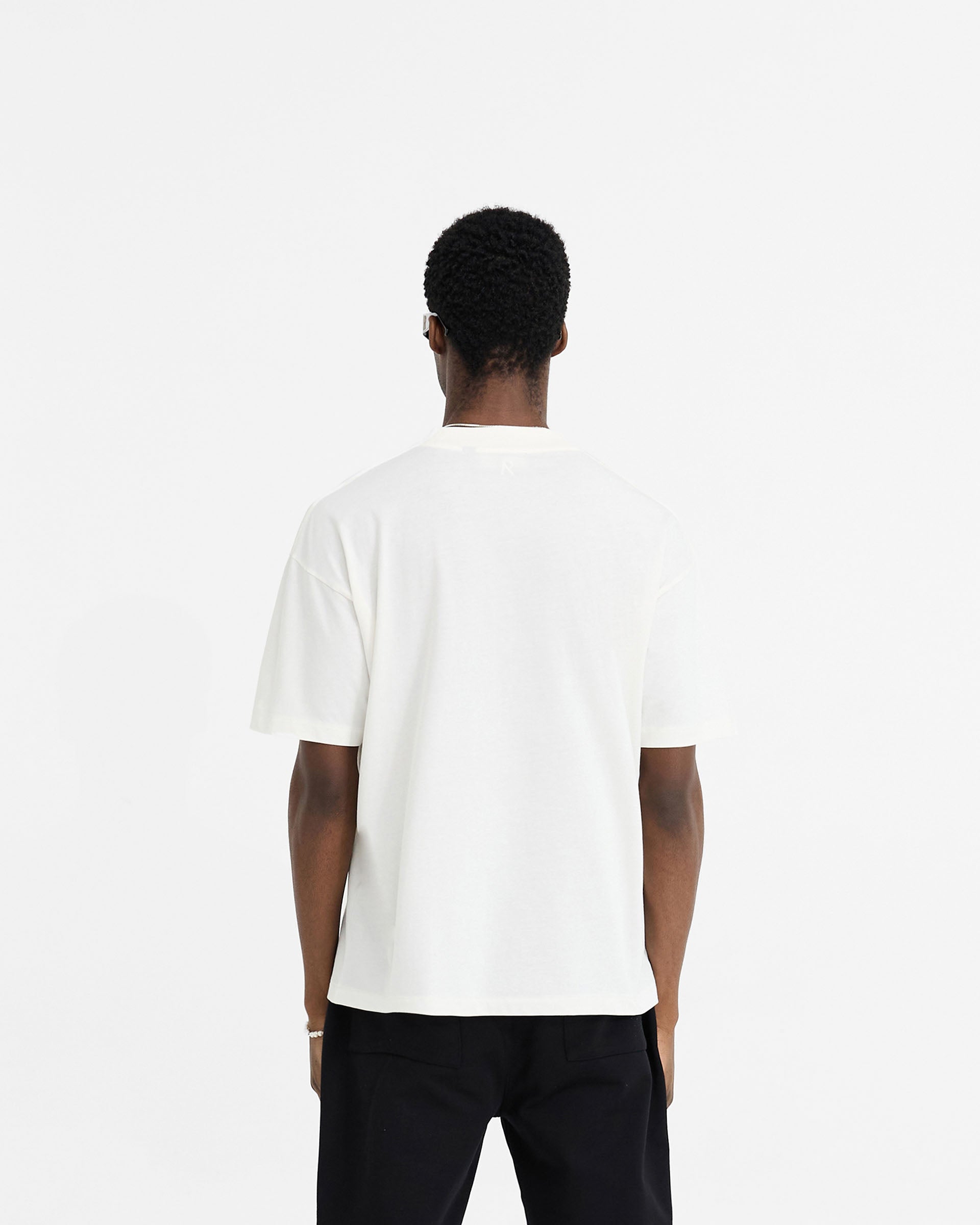 Man wearing a white oversized t-shirt on a plain white background | Initial Oversized T-Shirt in Flat White | Oversized t-shirt with Owners Club fit | Initial T-Shirts | Represent Clo