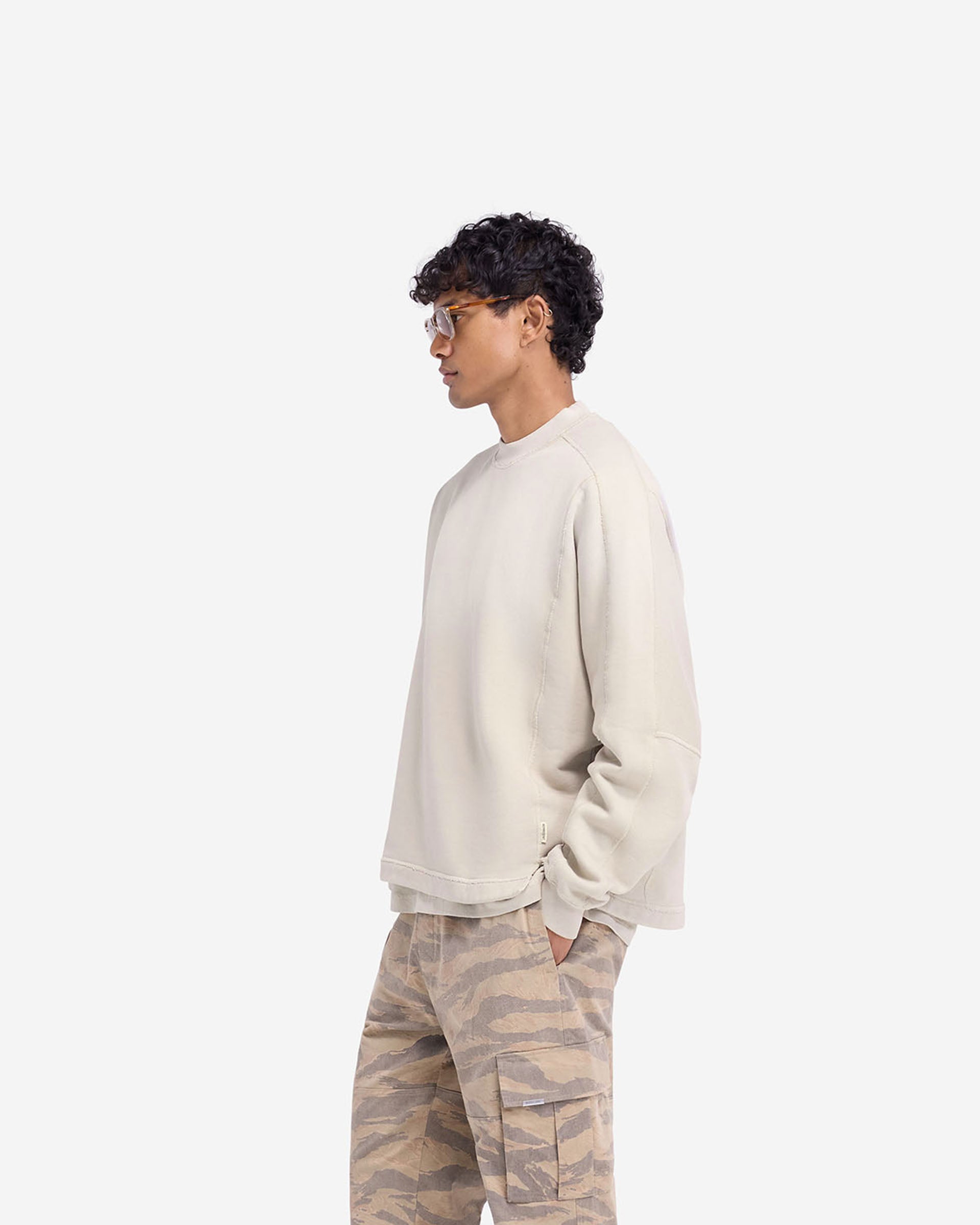 Man wearing an oversized oat sweatshirt on a plain white background | Stepped Hem Sweatshirt in Oat | Sweater with stepped hem and overlock seam | FW24 Sweaters | Represent Clo