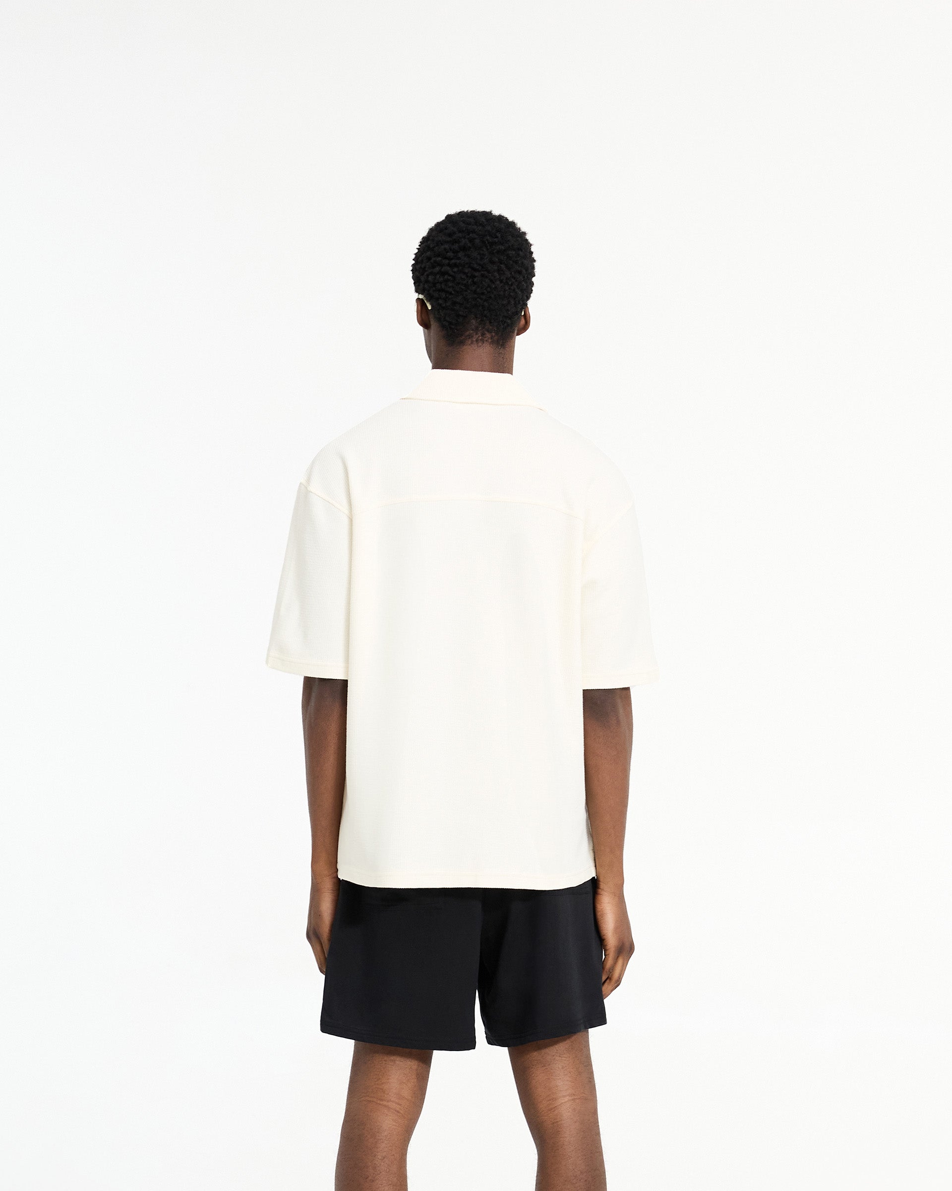 Man wearing a white waffle shirt on a plain white background | Waffle Shirt in Antique White | Drapey fit waffle shirt with revere collar | SC24 Shirts | Represent Clo