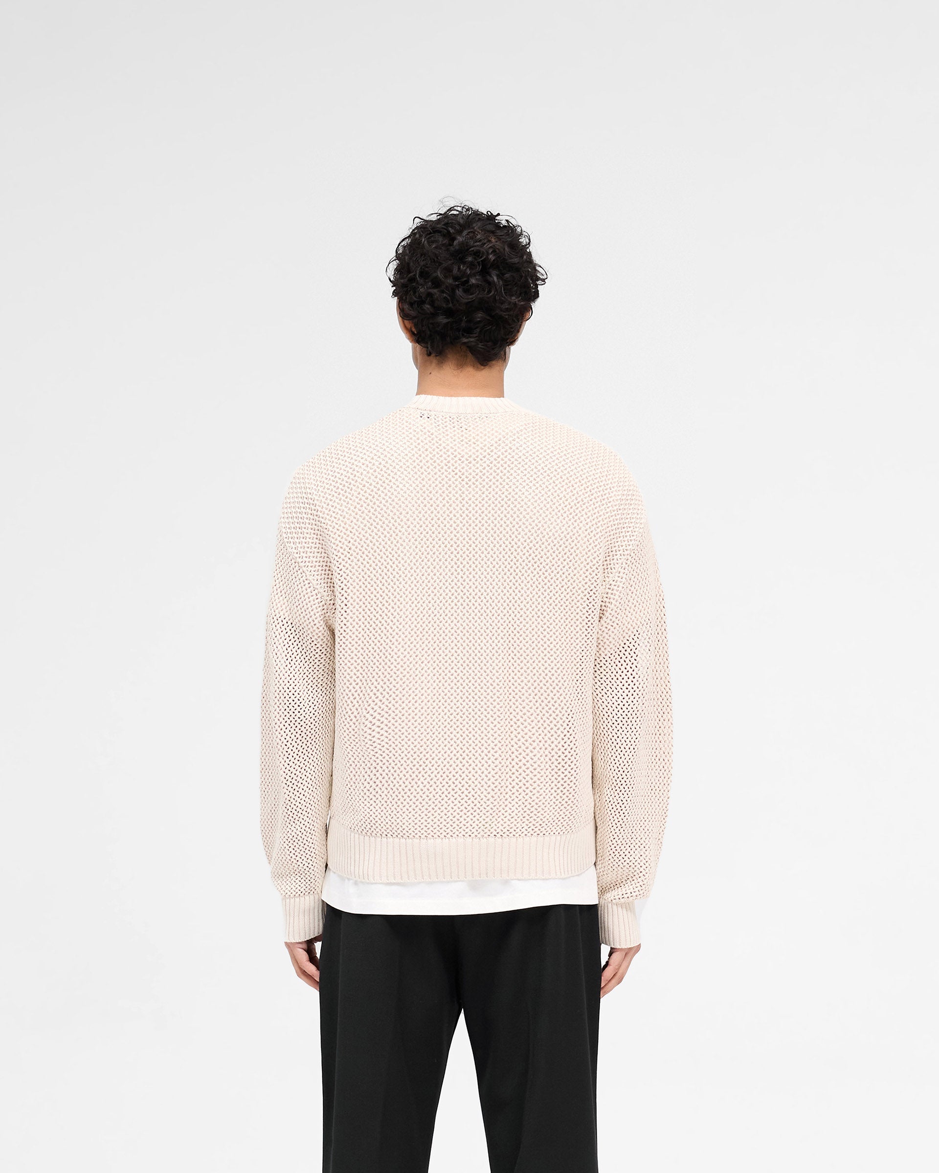 Man wearing an off white knit sweater on a plain white background | Open Gauge Knit Sweater in Off White | Slightly oversized open knit sweater | SS25 Knitwear | Represent Clo