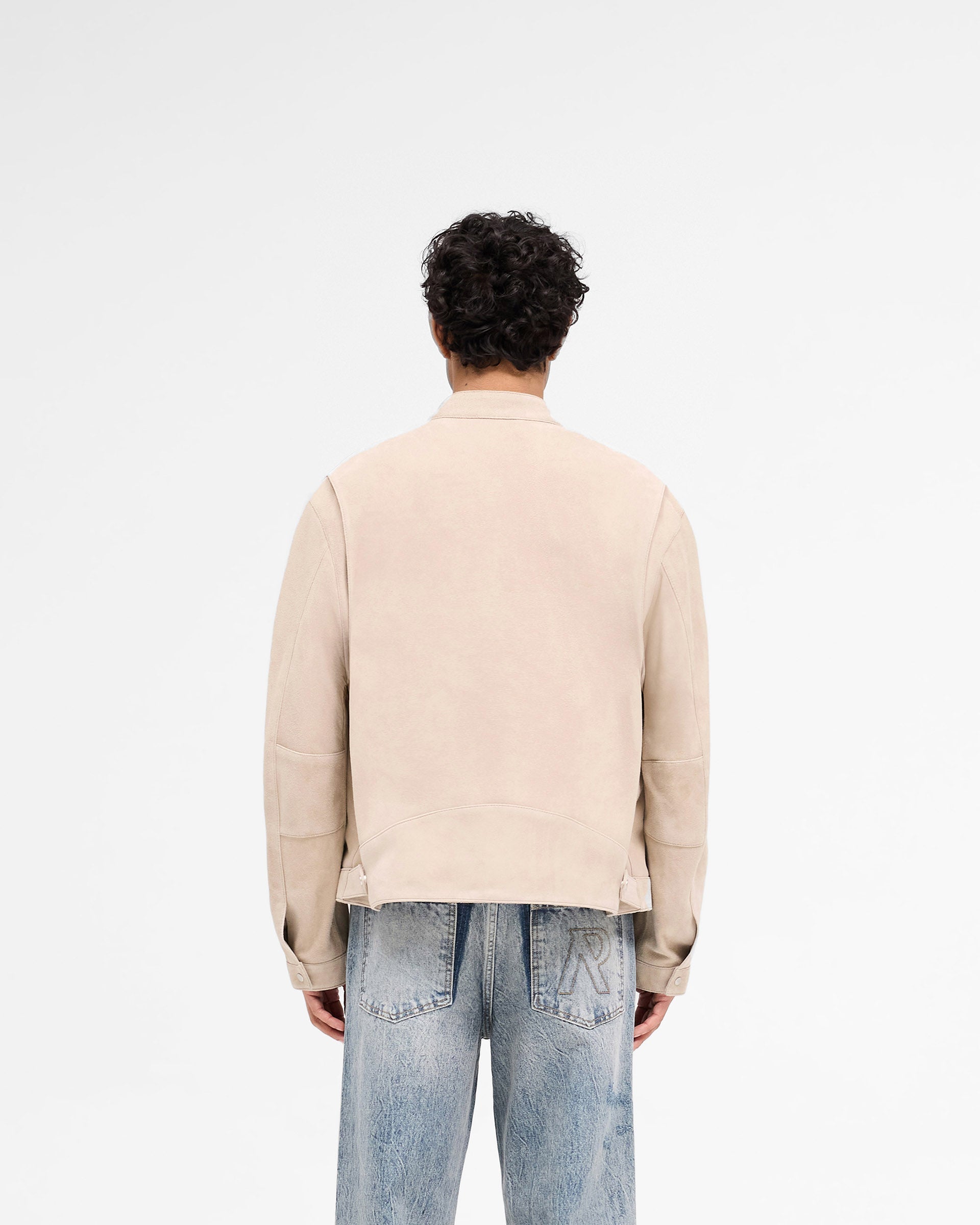 Man wearing a beige suede jacket on a plain white background | Overdrive Suede Jacket in Beige | Suede jacket with biker neck and vented shoulders | SS25 Outerwear | Represent Clo