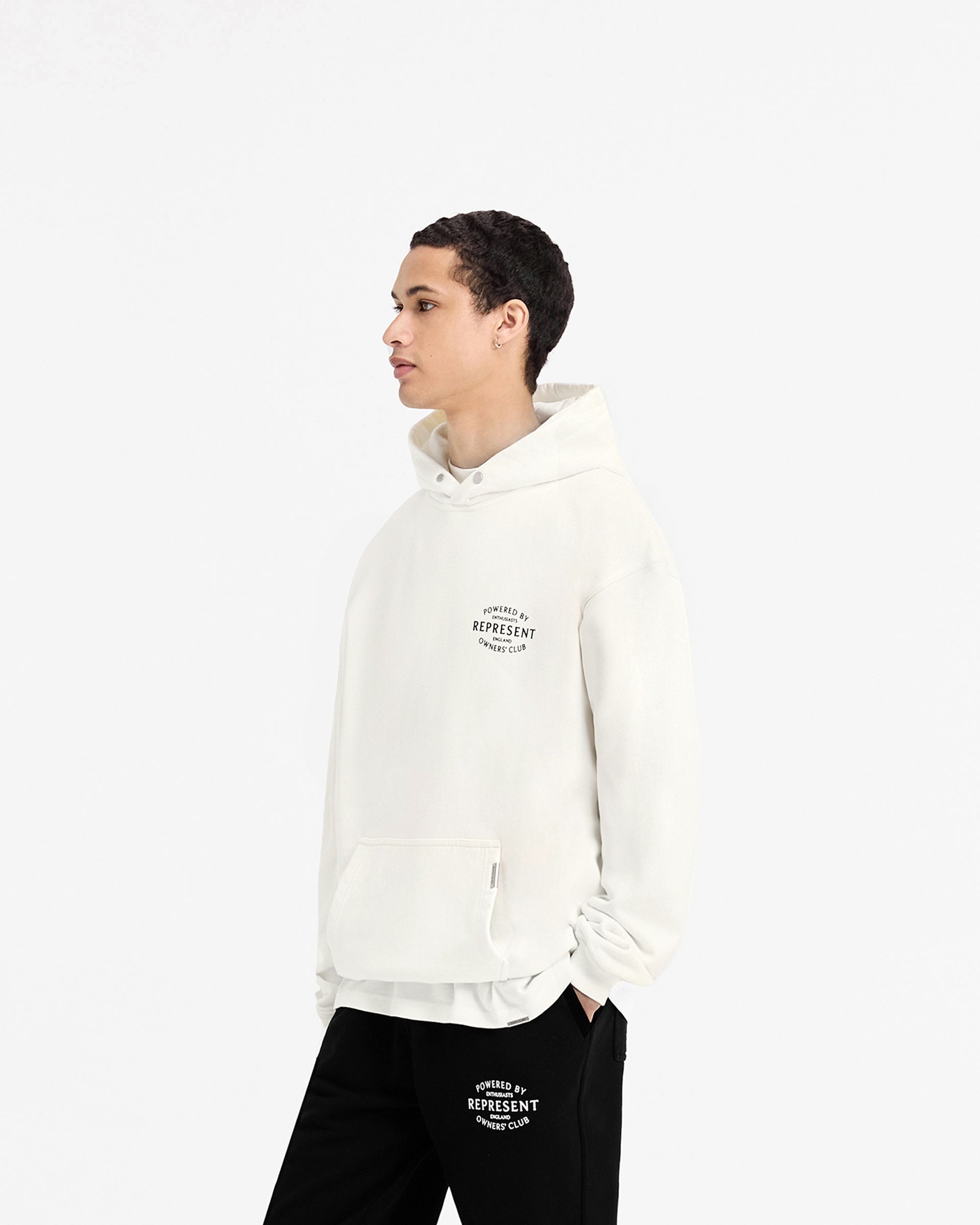 Man wearing a white hoodie on a plain white background | Represent Owners Club Stamp Hoodie in Flat White | Heavy weight hoodie with Cobrax popper and high build branding | Owners Club Hoodies | Represent Clo