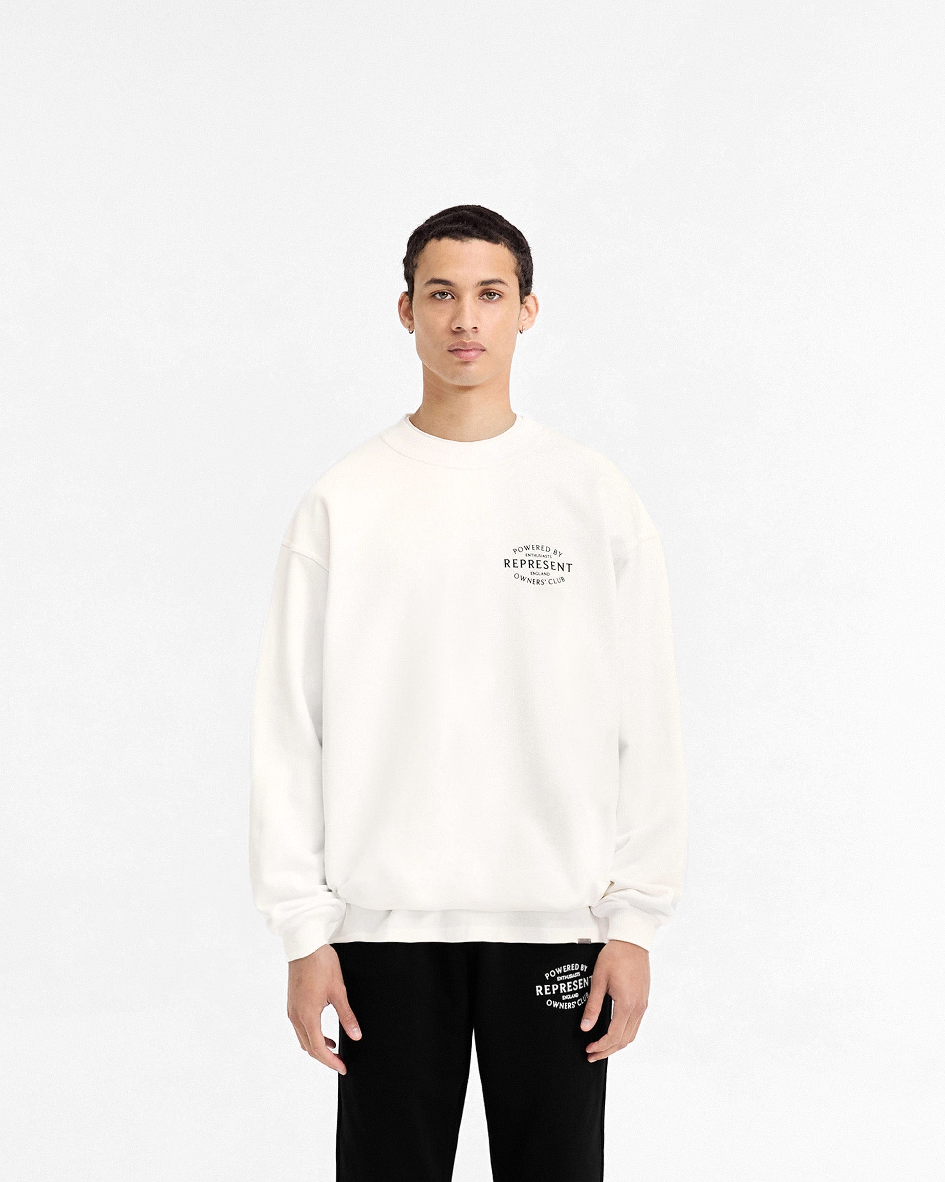 Man wearing a white sweater on a plain white background | Represent Owners Club Stamp Sweater in Flat White | Heavy weight jersey cotton oversized sweater | Owners Club Sweaters | Represent Clo