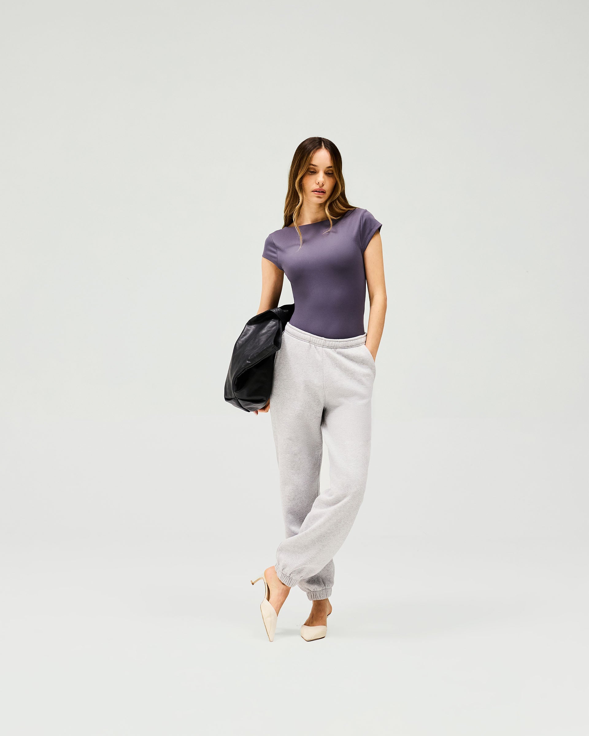 Woman wearing a grey bodysuit on a plain white background | Owners Club Bodysuit in Grey | Sculpting bodysuit with scoop back and cap sleeves | Womens Tops | Represent Clo