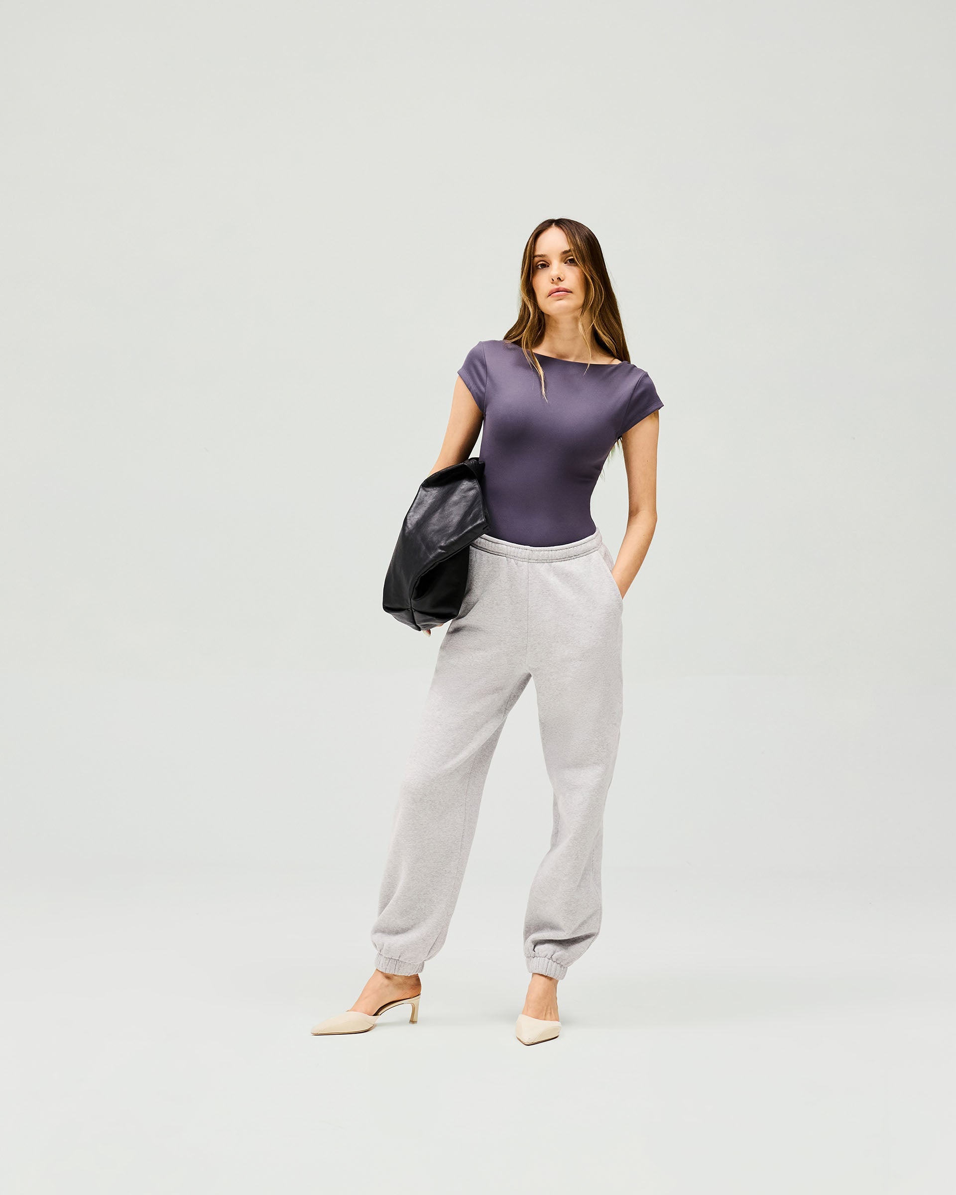 Woman wearing a grey bodysuit on a plain white background | Owners Club Bodysuit in Grey | Bodysuit with low scoop back and cap sleeves | Womens Tops | Represent Clo