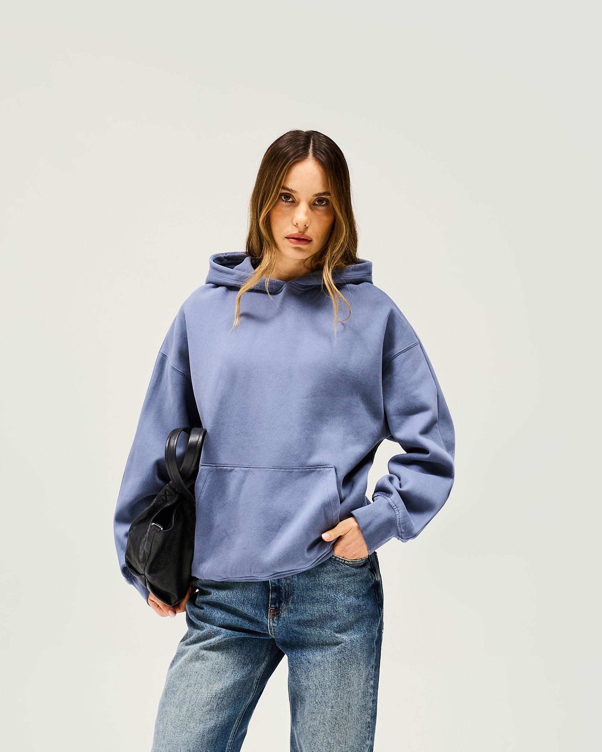 Woman wearing an oversized blue hoodie on a plain white background | Owners Club Boyfriend Hoodie in Steel Blue | Mid weight relaxed fit oversized hoodies | Womens Owners Club Hoodies | Represent Clo