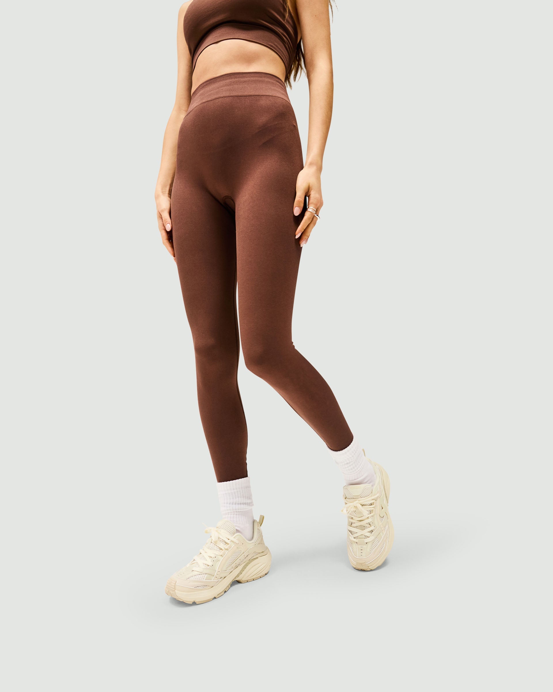 Woman wearing mocha leggings on a plain white background | Owners Club Contour Seamless Legging in Mocha | High waisted seamless leggings | Womens Bottoms | Represent Clo