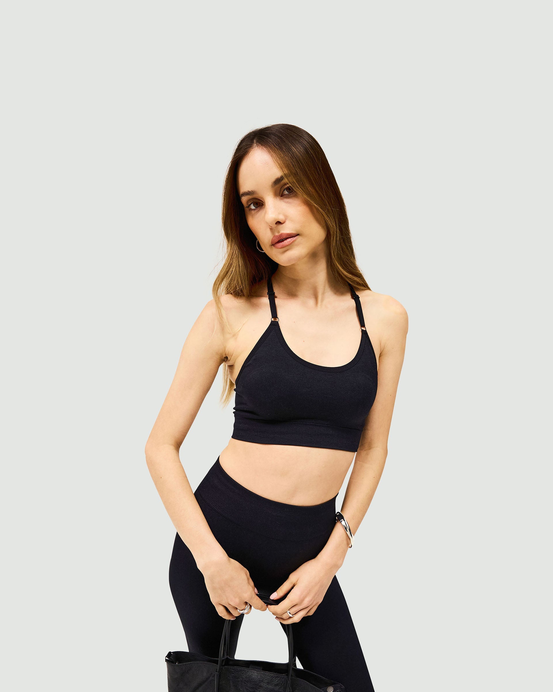 Woman wearing a black seamless low impact bra on a plain white background | Owners Club Seamless Low Impact Bra in Jet Black | Bra with engineered contouring and adjustable straps | Womens Owners Club Tops | Represent Clo