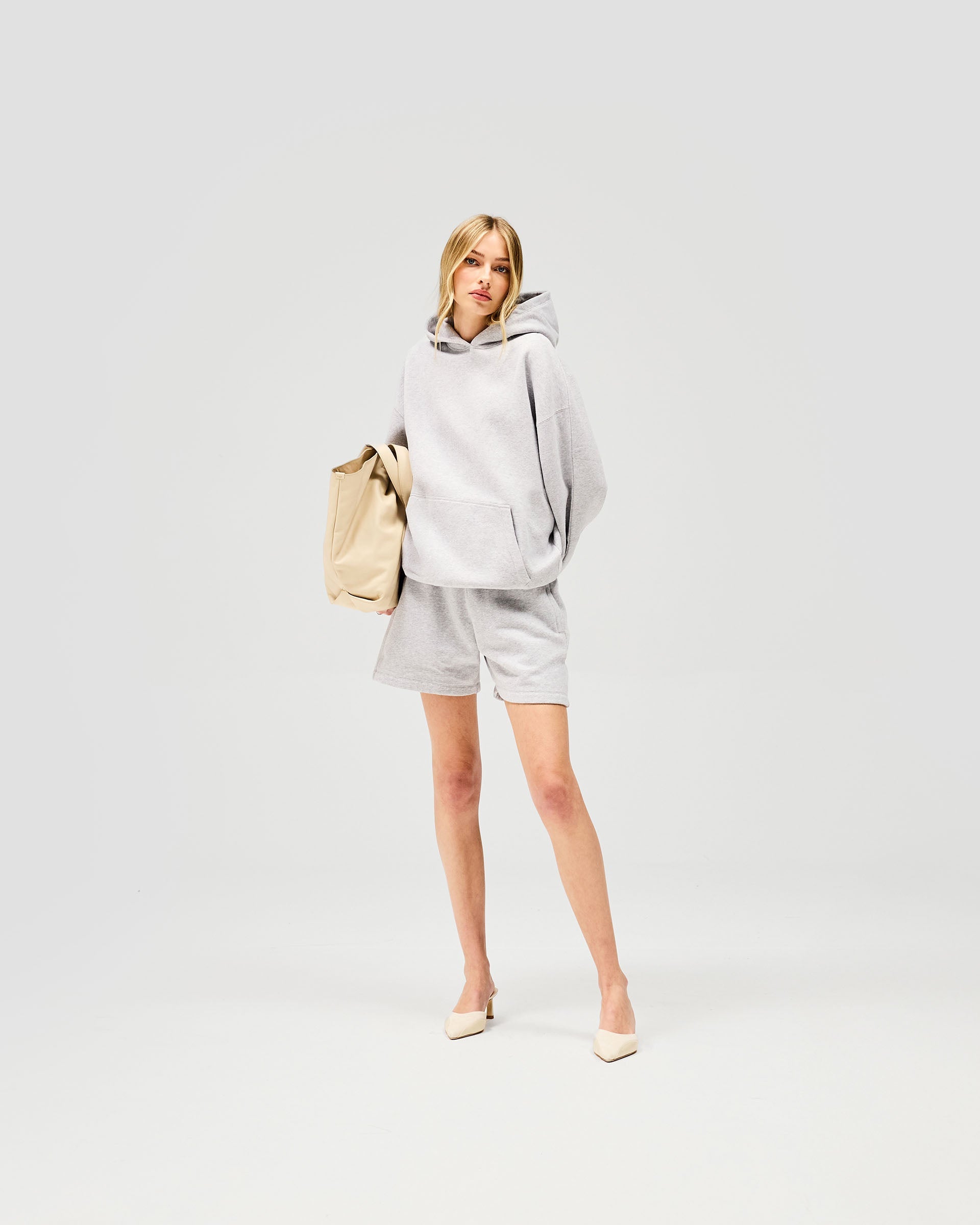 Woman wearing grey shorts on a plain white background | Owners Club Short in Grey Marl | Sweat mini shorts with internal drawcord and side pockets | Womens Owners Club Shorts | Represent Clo