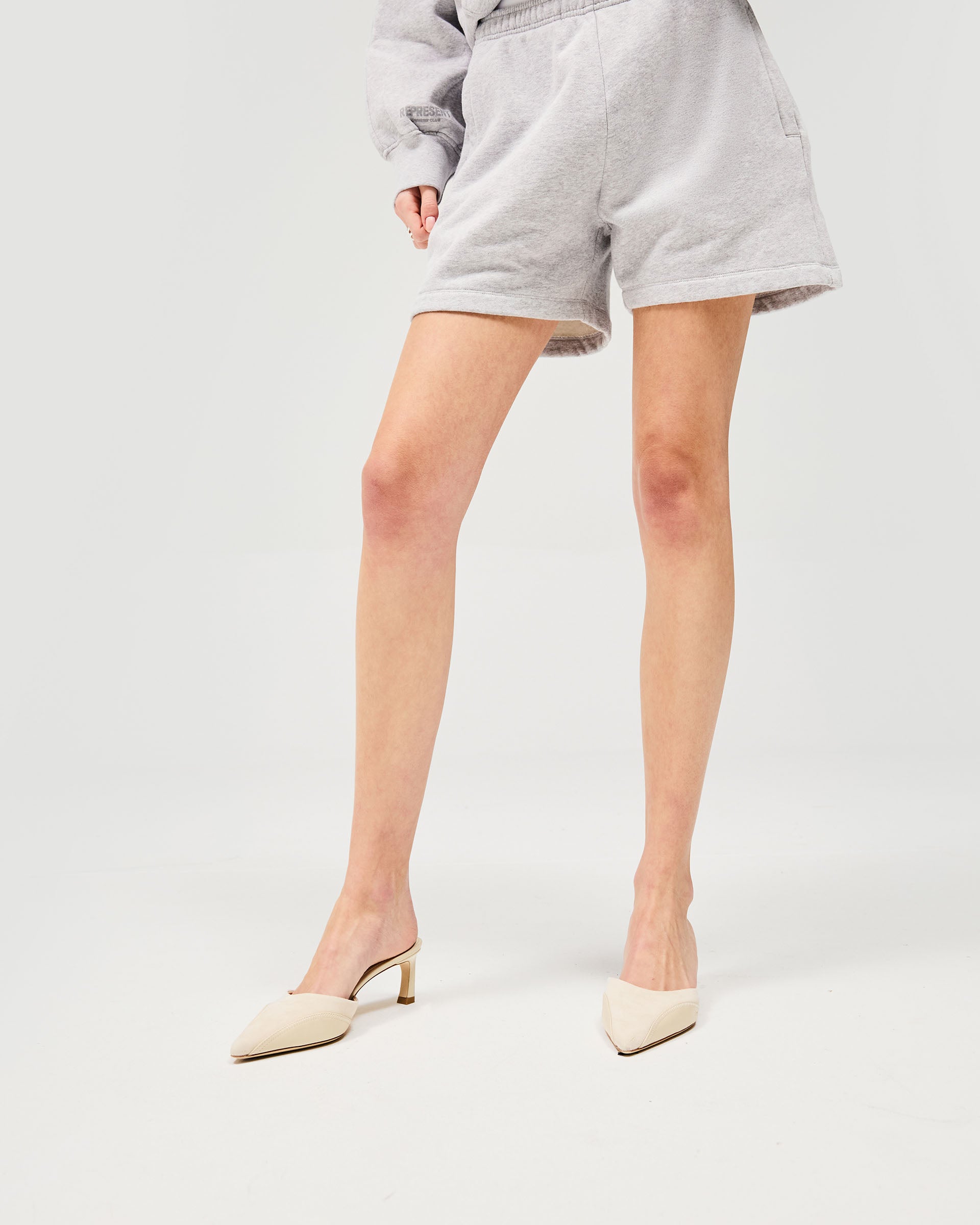 Woman wearing grey shorts on a plain white background | Owners Club Short in Grey Marl | Sweat shorts with internal drawcord and side pockets | Womens Owners Club Shorts | Represent Clo