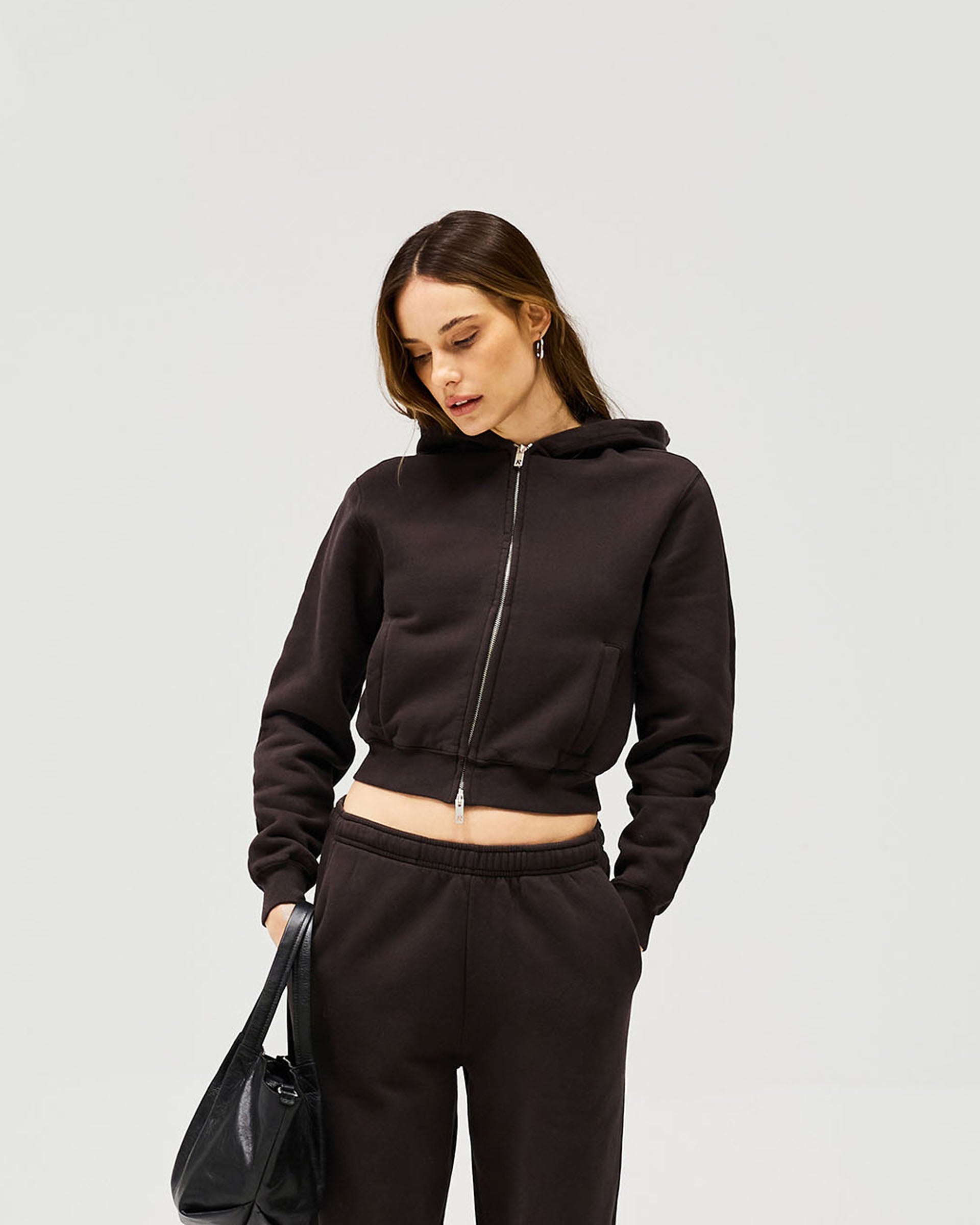 Woman wearing a black slim zip hoodie on a plain white background | Owners Club Slim Zip Hoodie in Black Coffee | Cropped slim fit zip through hoodie | Womens Owners Club Hoodies | Represent Clo