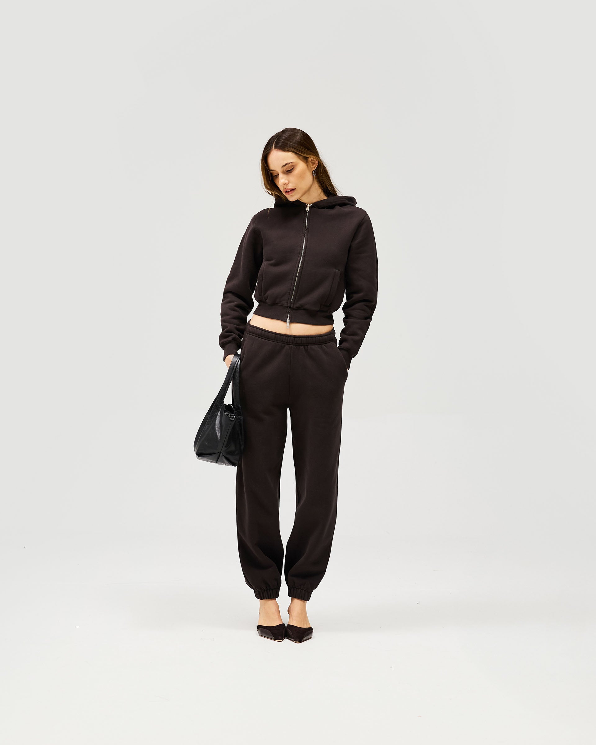 Woman wearing a black zip hoodie on a plain white background | Owners Club Slim Zip Hoodie in Black Coffee | Cropped slim fit zipped hoodie | Womens Owners Club Hoodies | Represent Clo