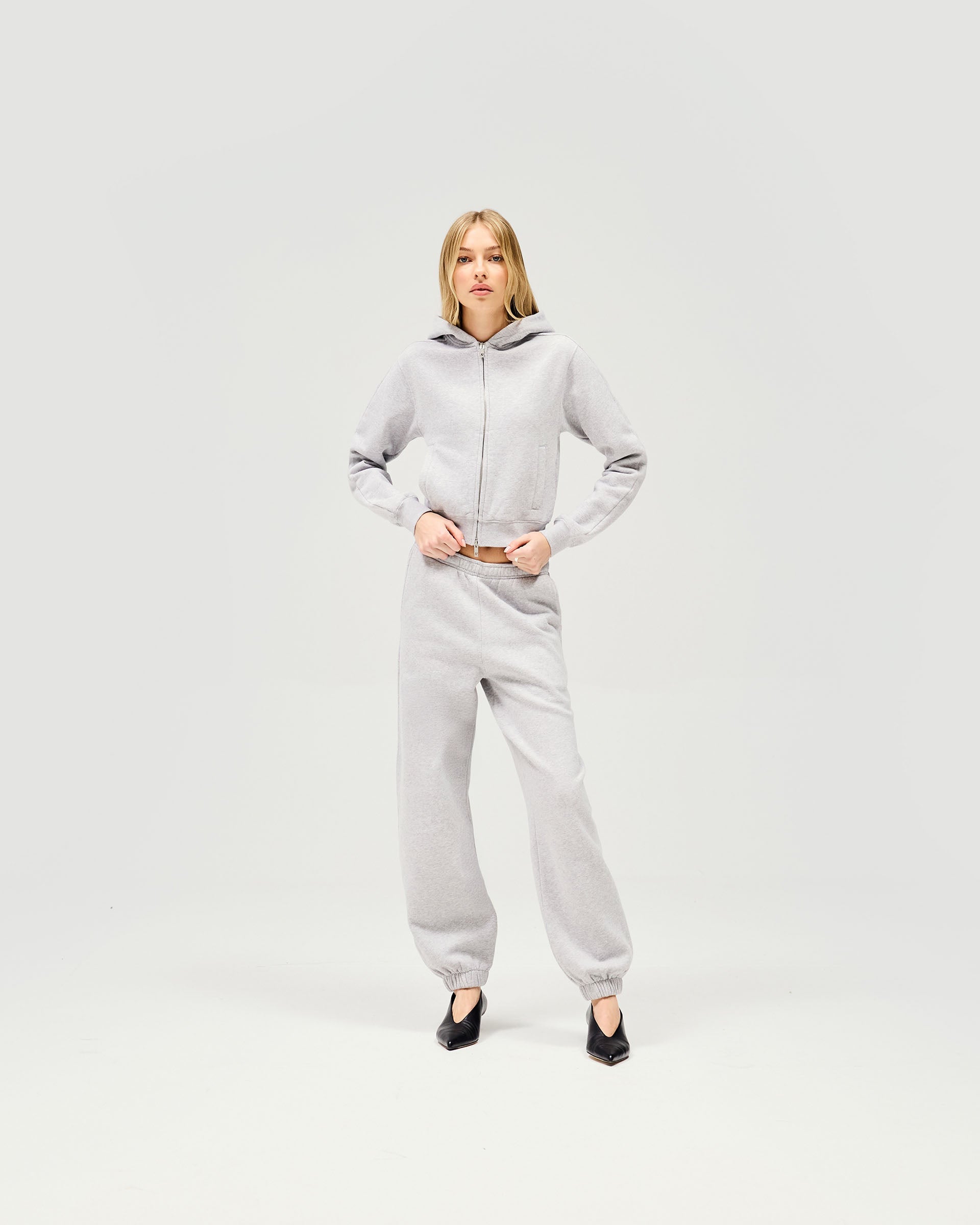 Woman wearing a grey zip hoodie on a plain white background | Owners Club Slim Zip Hoodie in Grey Marl | Slim fit cropped zip through hoodie | Womens Owners Club Hoodies | Represent Clo