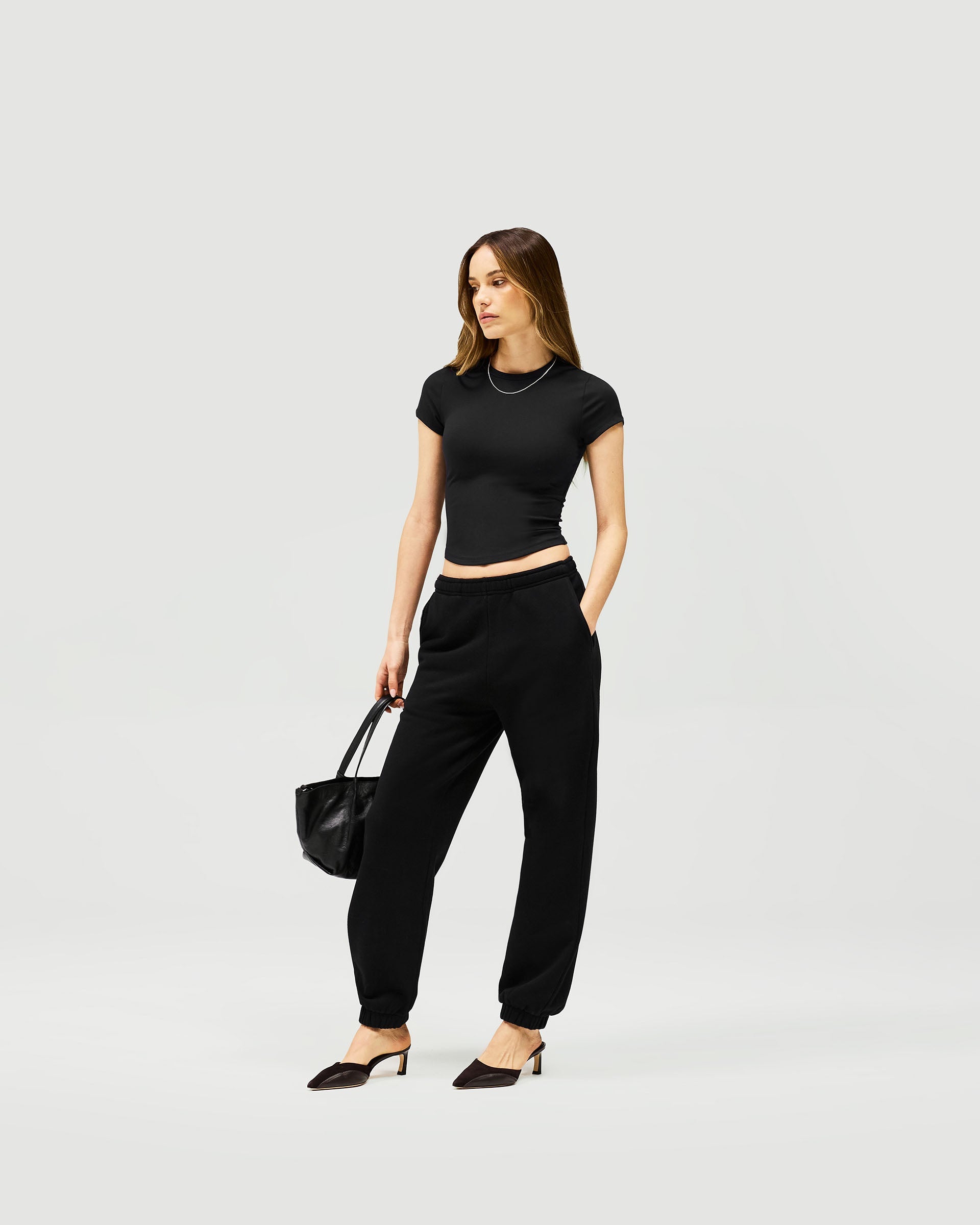 Woman wearing black track pants on a plain white background | Owners Club Track Pant in Jet Black | Sweatpants with elasticised waist and leg hems | Womens Owners Club Bottoms | Represent Clo