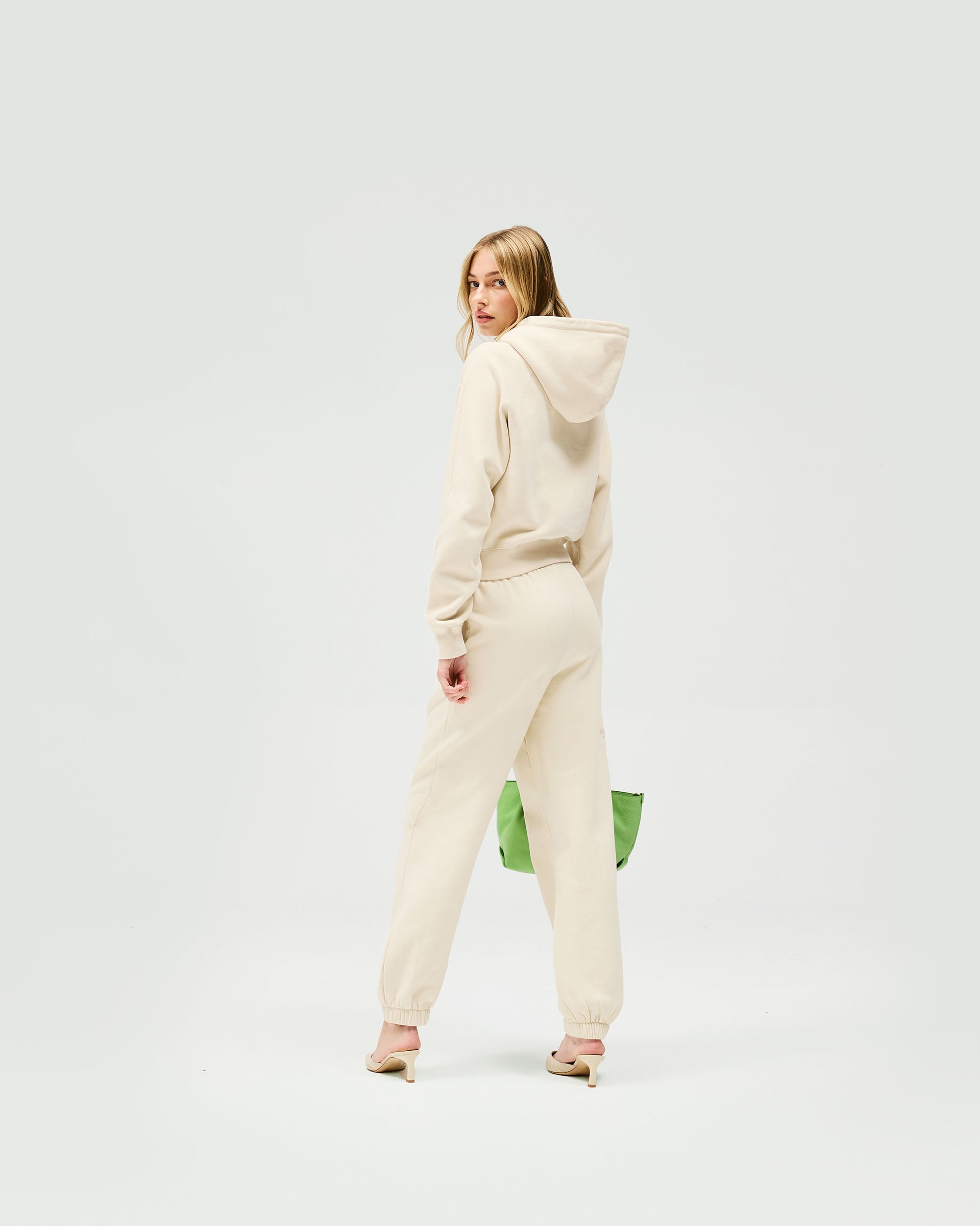 Woman wearing relaxed fit oat track pants on a plain white background | Owners Club Track Pant in Oat Milk | Track pants with elasticised waist and leg hem | Womens Owners Club Bottoms | Represent Clo