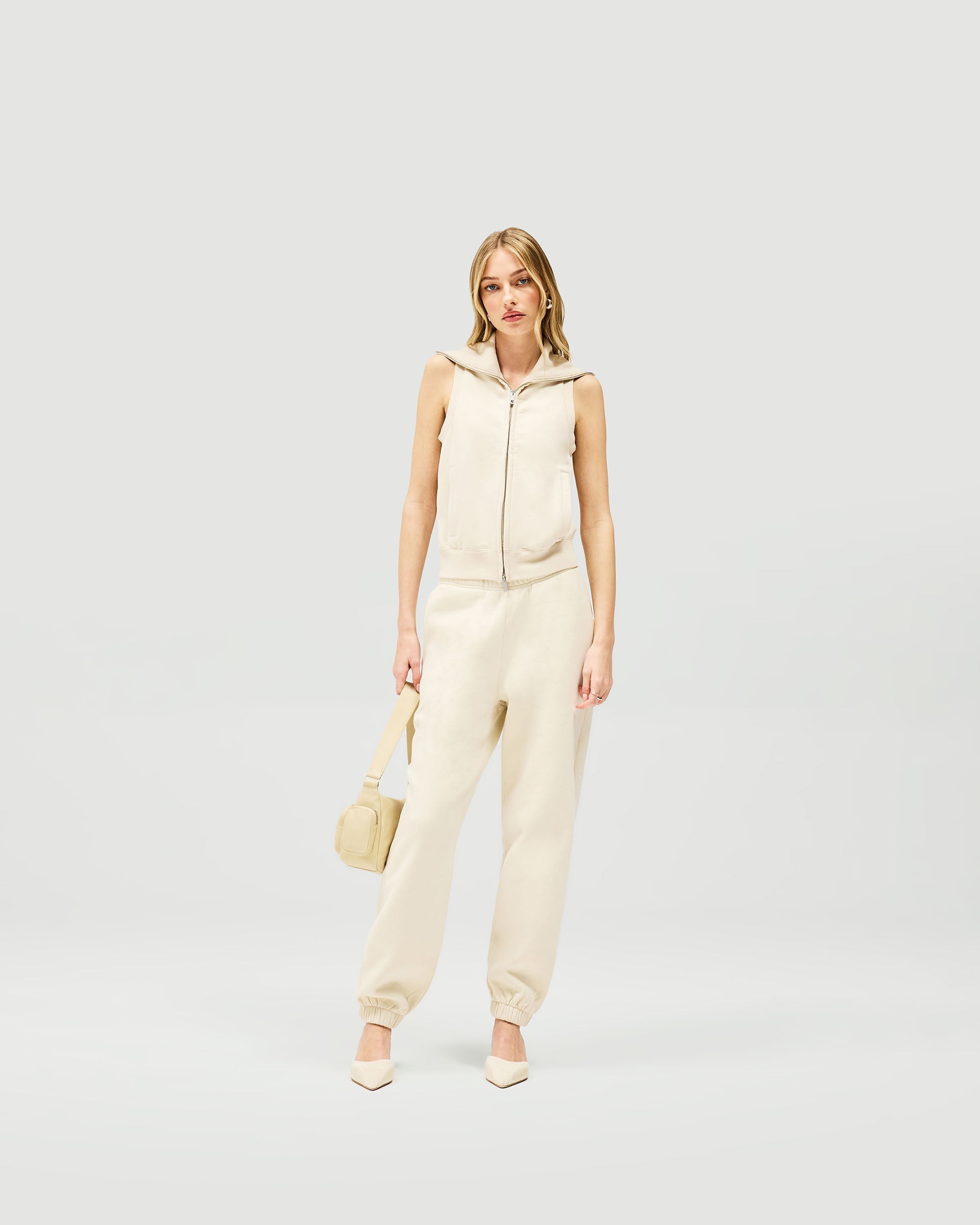 Woman wearing a slim fit cream gilet on a plain white background | Owners Club Gilet in Oat Milk | Gilet with double ended zipper and welt pockets | Womens Owners Club Outerwear | Represent Clo