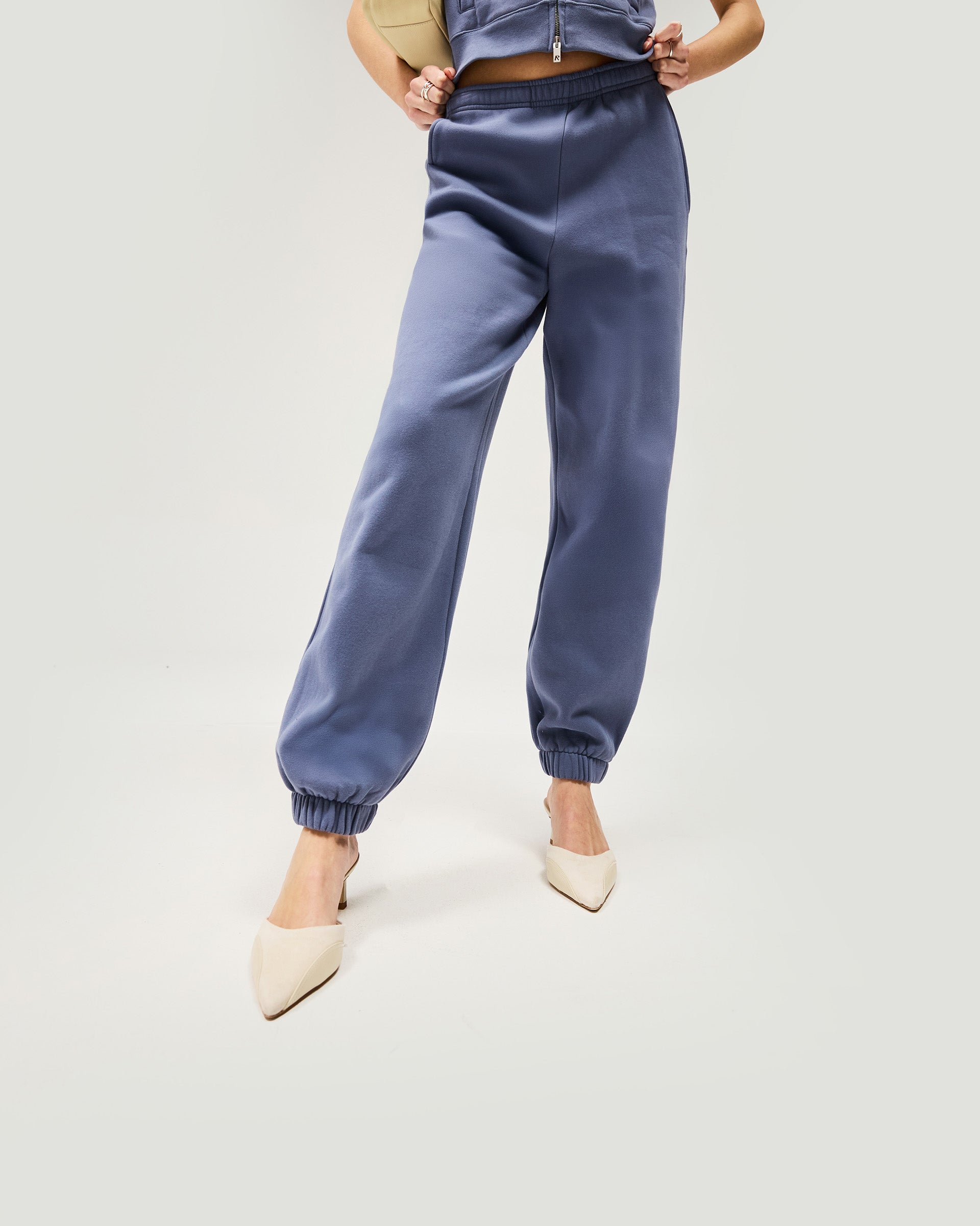 Woman wearing relaxed fit steel blue track pants on a plain white background | Owners Club Track Pant in Steel Blue | Track pants with elasticised waist | Womens Owners Club Bottoms | Represent Clo