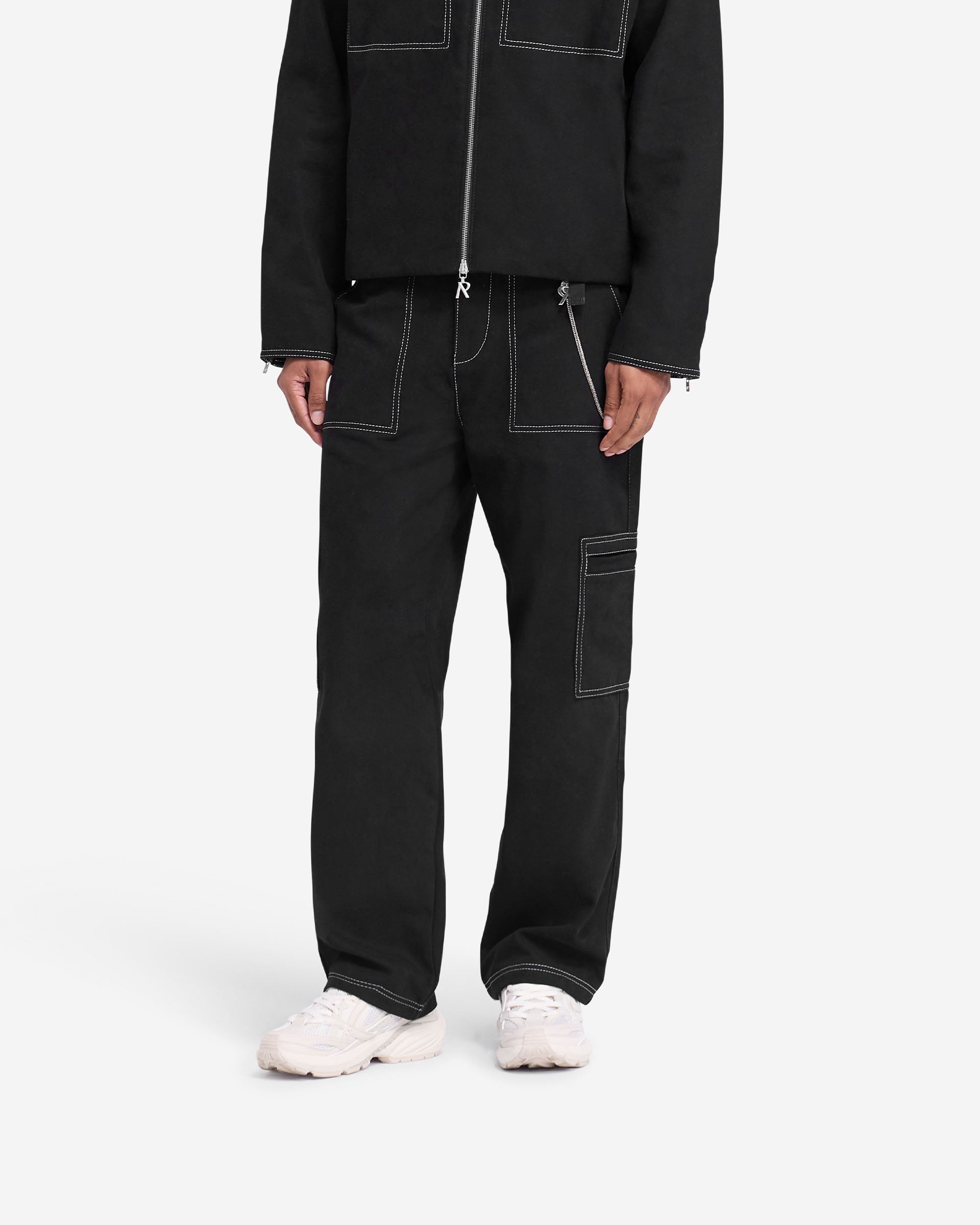 Man wearing black pants with contrast stitching on a plain white background | Contrast Stitch Pant in Jet Black | Cotton twill relaxed straight leg pants | FW24 Pants | Represent Clo