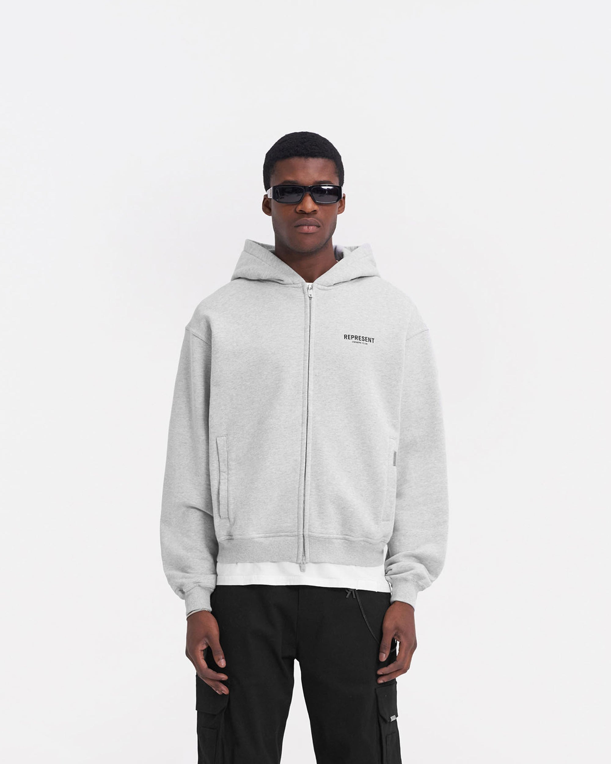 Man wearing a grey zip hoodie on a plain white background | Represent Owners Club Zip Hoodie in Ash Grey | Oversized zip hoodie with ribbed trims | Owners Club Hoodies | Represent Clo