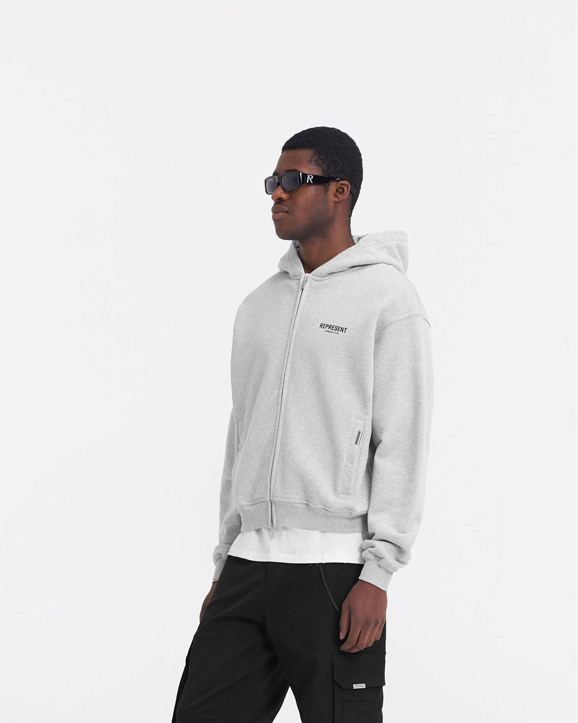 Man wearing a grey zip hoodie on a plain white background | Represent Owners Club Zip Hoodie in Ash Grey | Oversized zip hoodie with ribbed trims | Owners Club Hoodies | Represent Clo