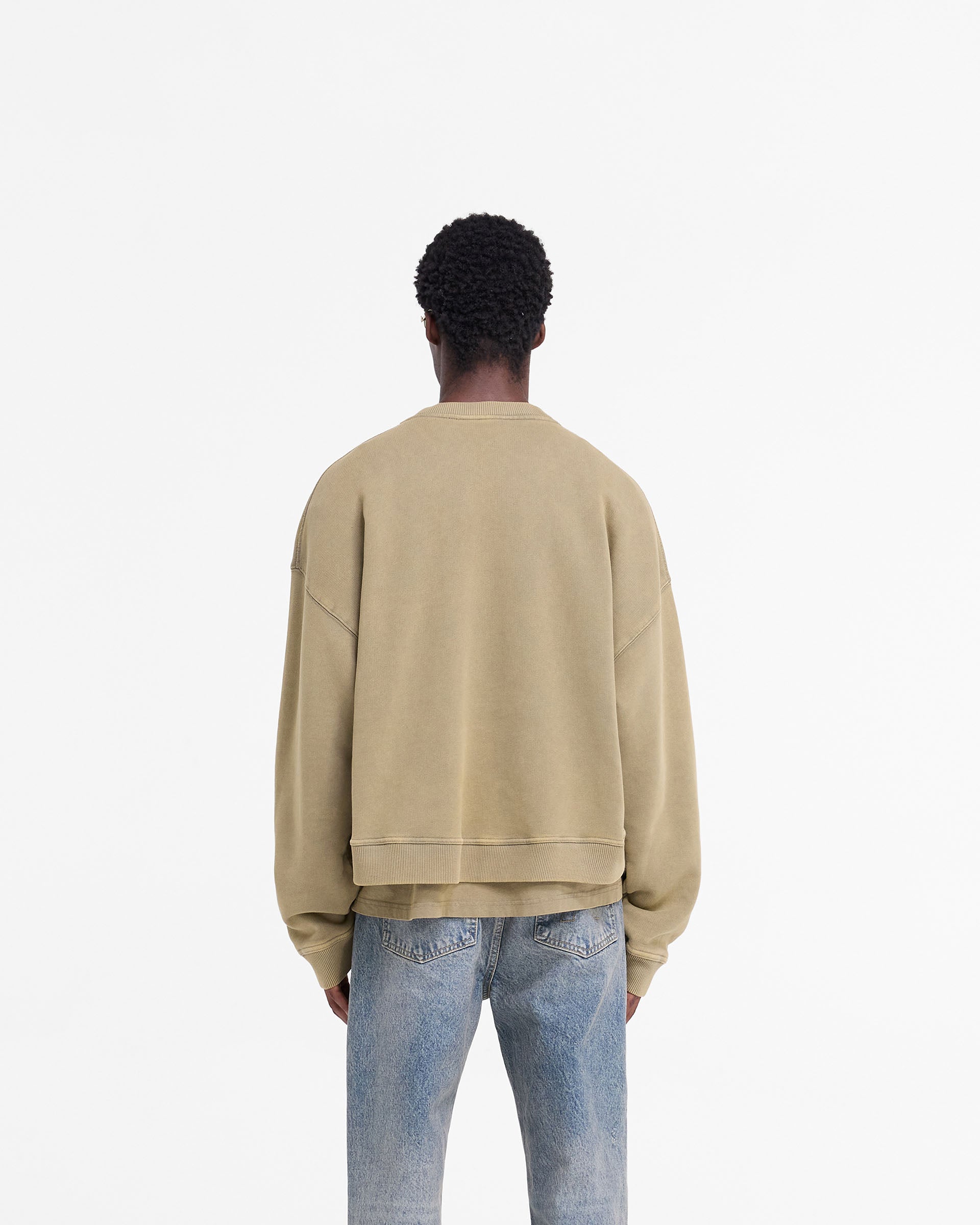 Man wearing an oversized fawn sweater on a plain white background | Rep Applique Sweater in Fawn | Boxy fit sweater with distressed applique logo | FW24 Sweaters | Represent Clo