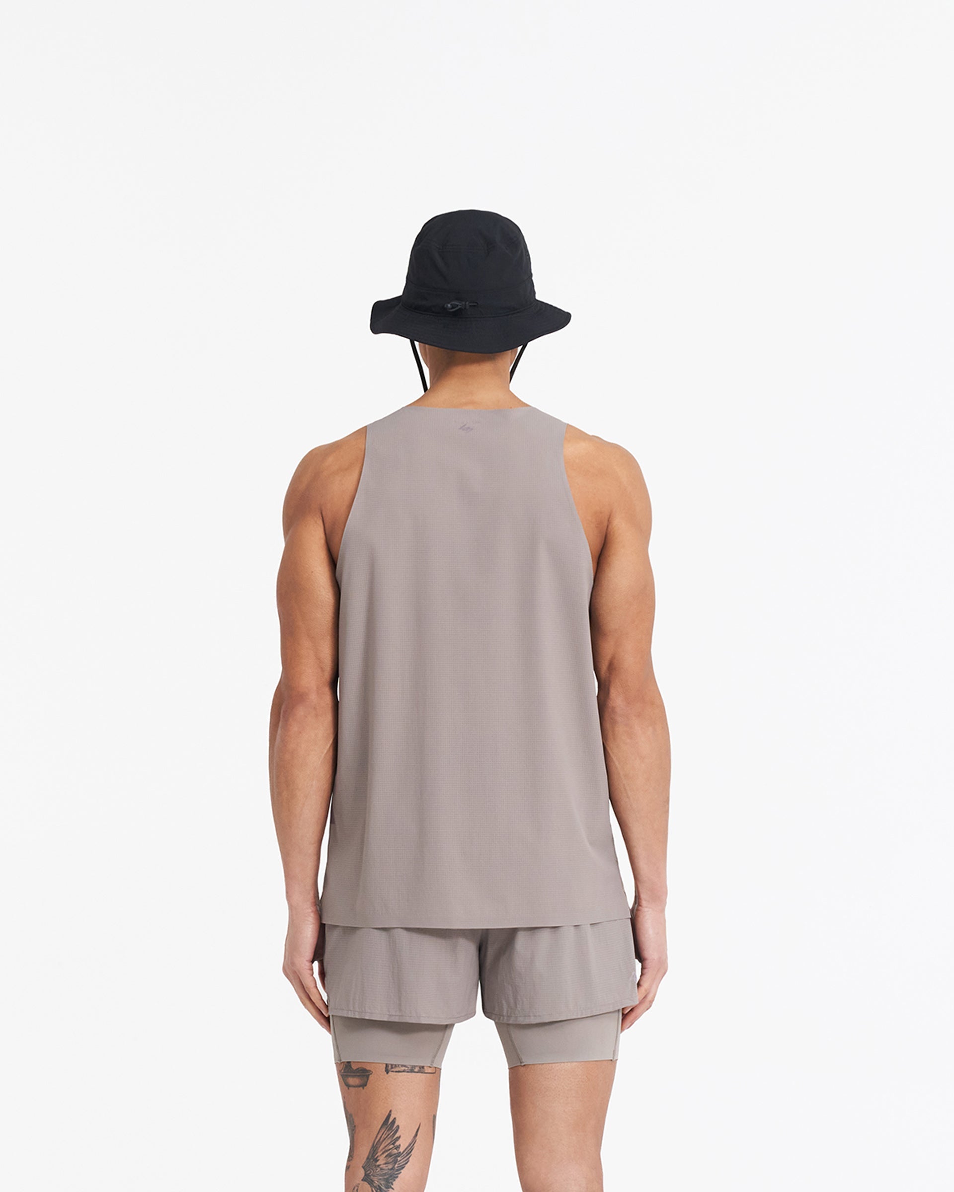 Man wearing a grey perforated training vest on a plain white background | 247 Singlet in Cinder | Stretch ripstop vest with bonded hems and flatlock seams | 247 T-Shirts | Represent Clo