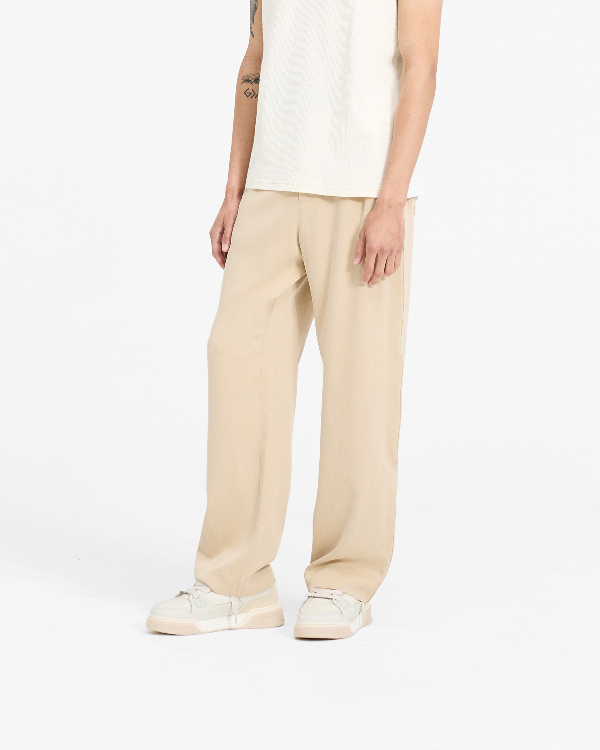 Man wearing latte brown straight leg pants on a plain white background | Resort Pant in Latte | Straight leg pants with hybrid waistband | SC24 Pants | Represent Clo