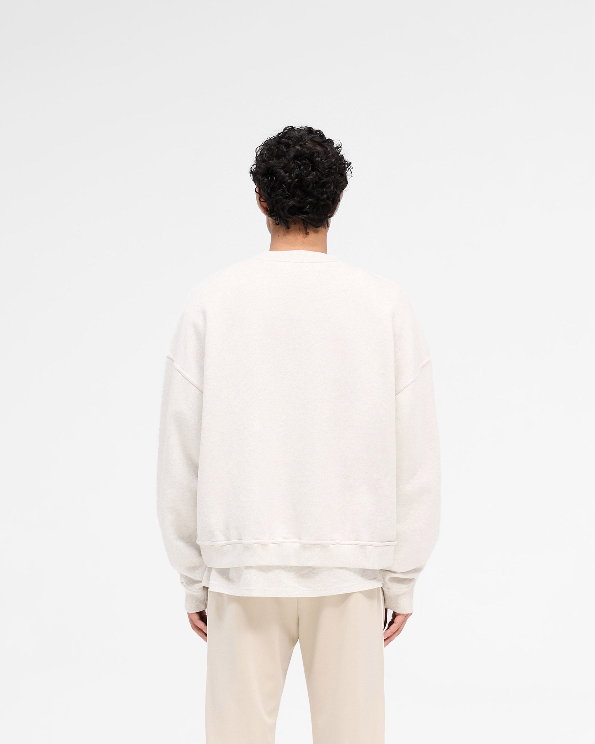 Man wearing a cream sweater on a plain white background | Rep Applique Sweater in Cream Marl | Sweater with textured applique and boxy fit | SS25 Sweaters | Represent Clo