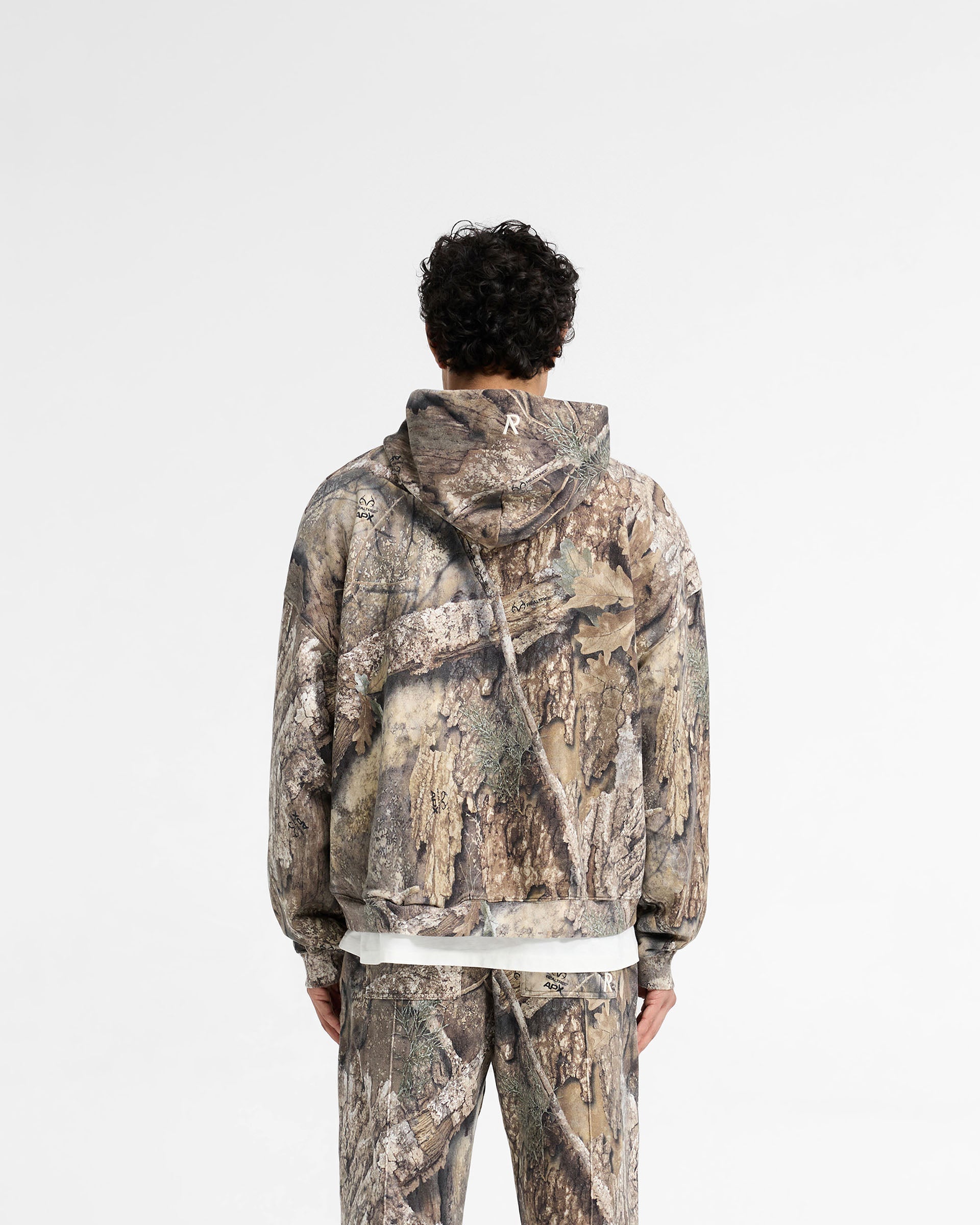Man wearing a camo zip up hoodie on a plain white background | Realtree Zip Up Camo Boxy Hoodie in Camo | Oversized boxy fit zip up hoodie | SS25 Hoodies | Represent Clo