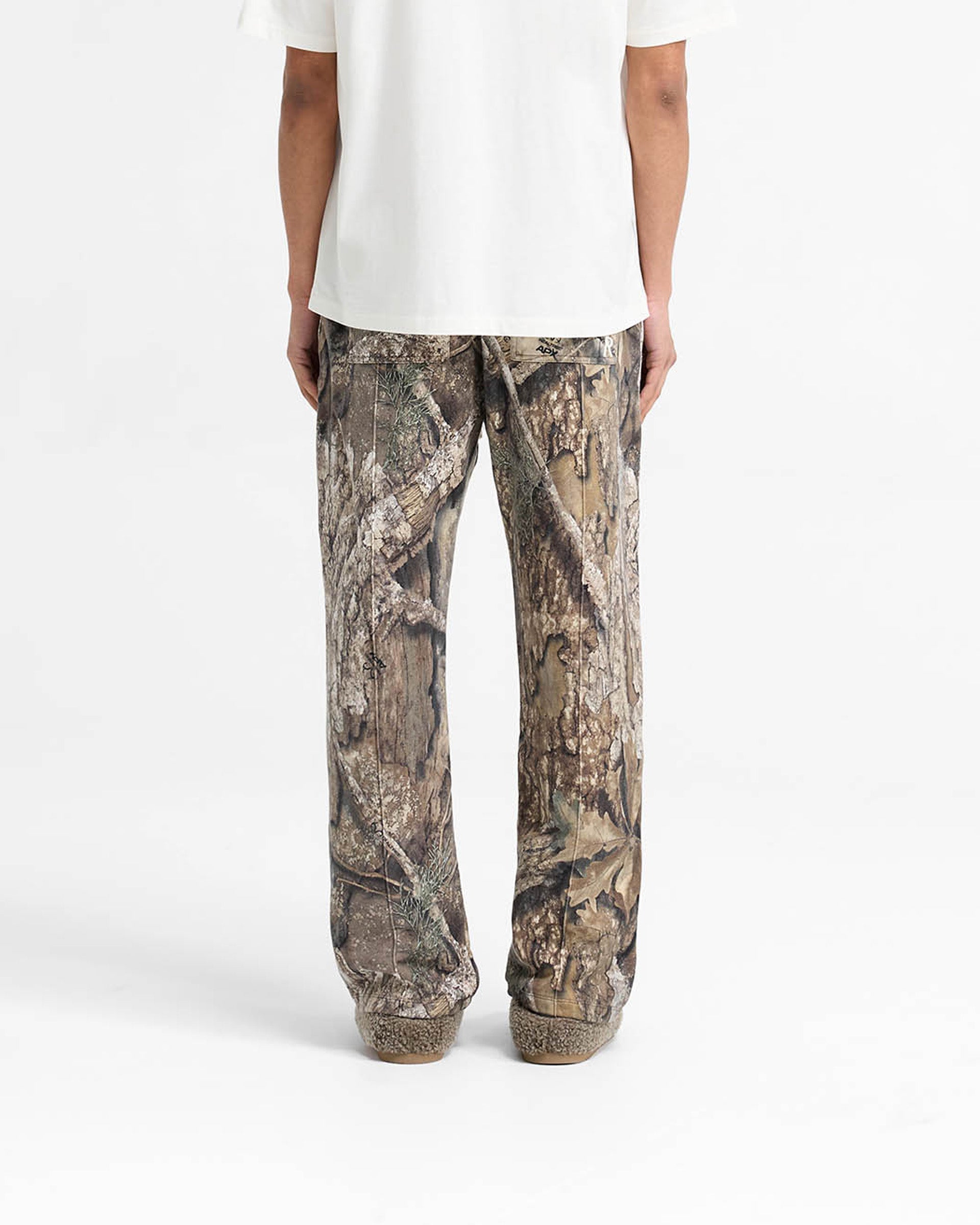 Man wearing camo sweatpants on a plain white background | Realtree Camo Sweatpants in Camo | Wide leg sweatpants with pintuck and elasticated waistband | SS25 Pants | Represent Clo