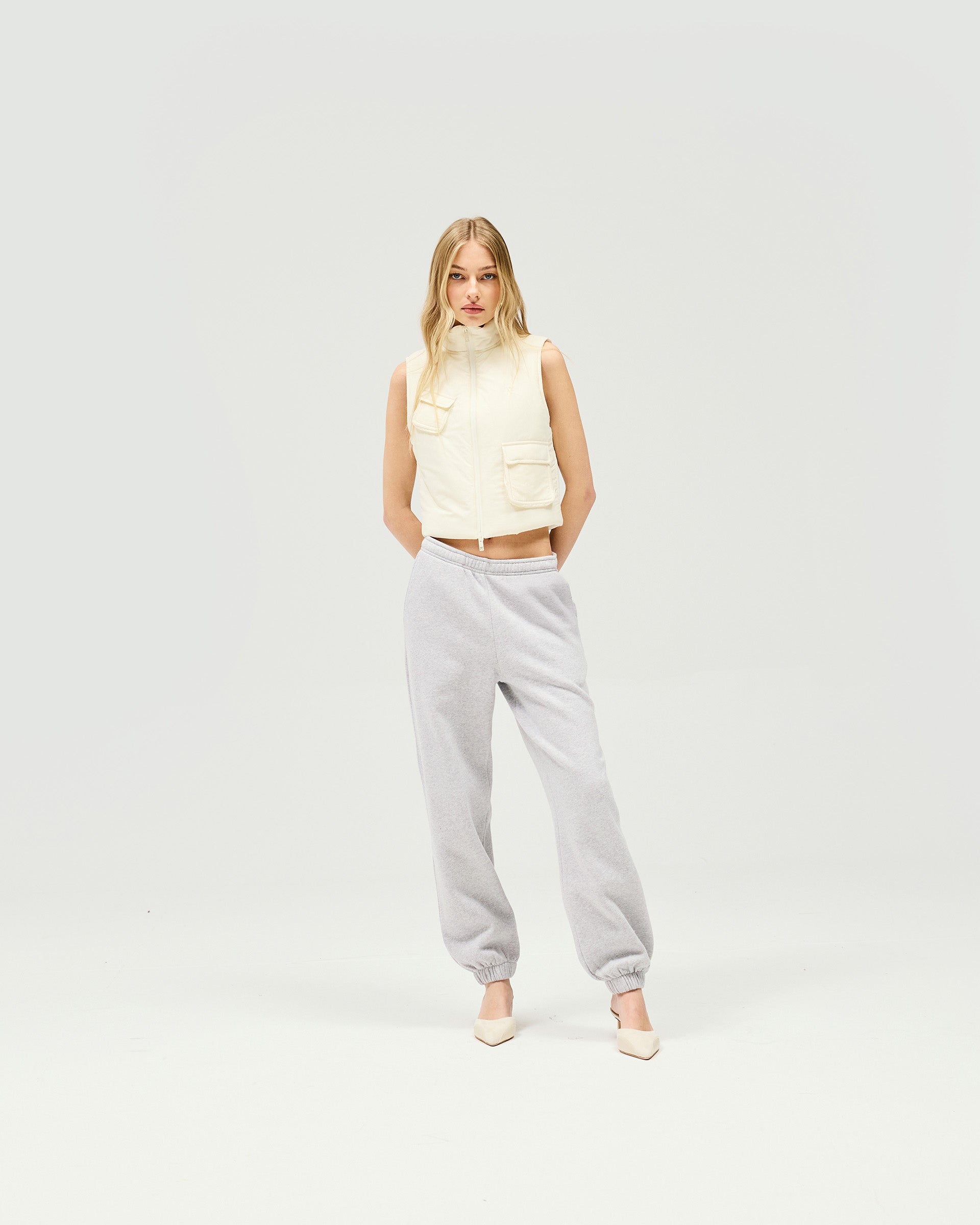 Woman wearing a warm white gilet on a plain white background | Revolver Gilet in Warm White | Shrunken fit gilet with recycled down and double front zip closure | Womens SS25 Outerwear | Represent Clo