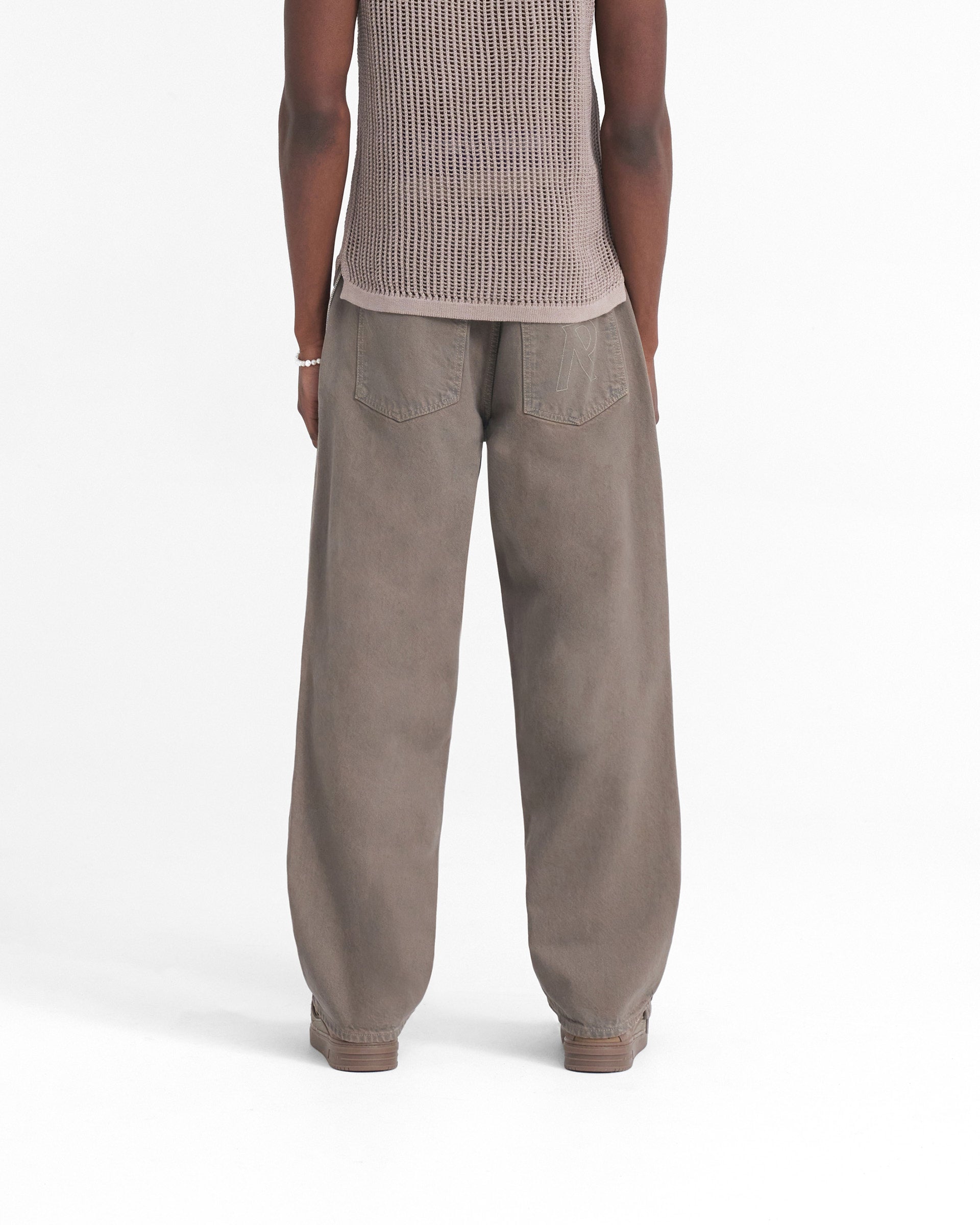 Man wearing baggy grey denim jeans on a plain white background | R3 Baggy Denim in Rock | Relaxed fit denim with heavy wash and branded trims | SS24 Denim | Represent Clo