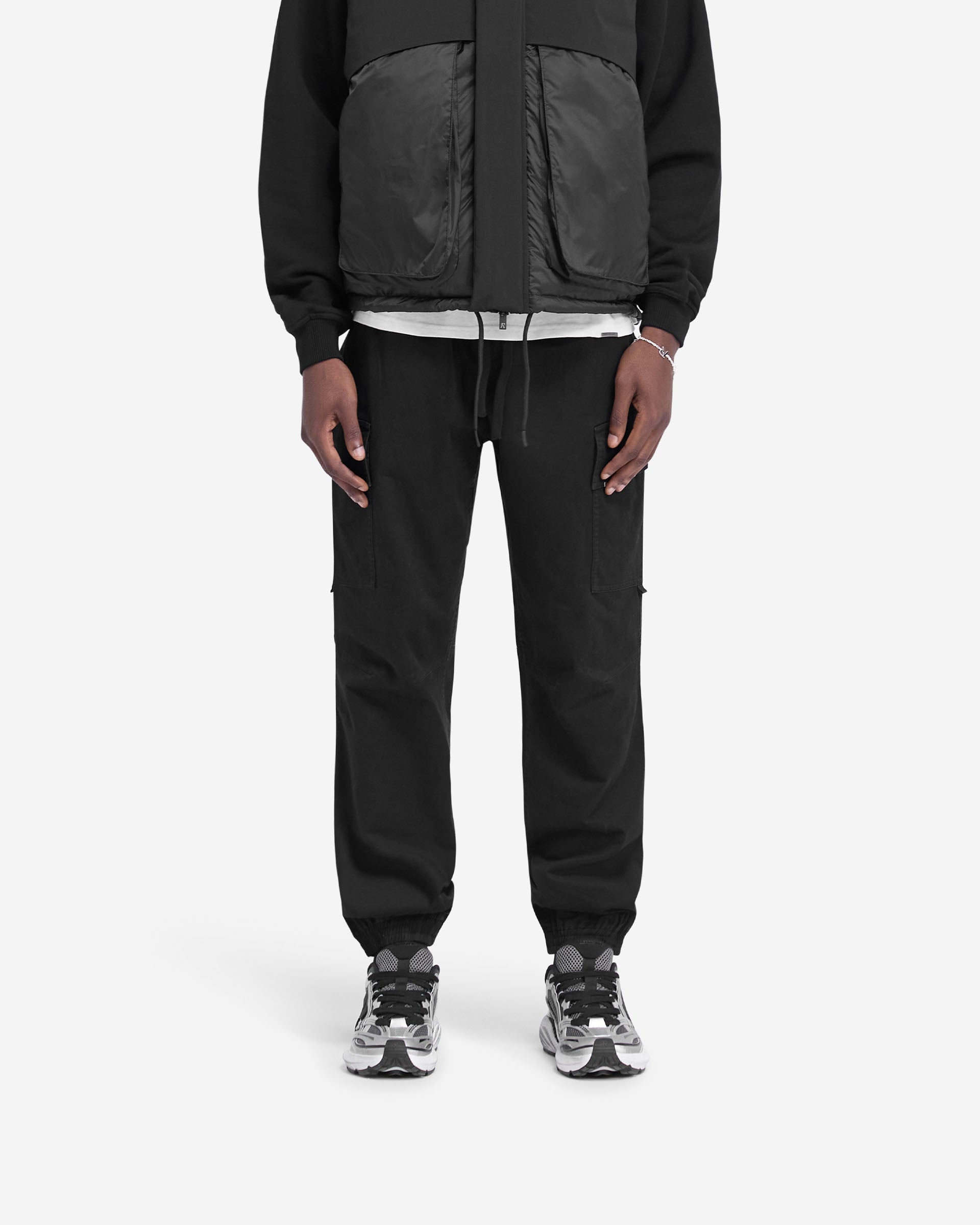 Man wearing black cuffed cargo pants on a plain white background | Cuffed Cargo Pant in Black | Cargo pants with elasticated waistband and cuffs | FW24 Pants | Represent Clo