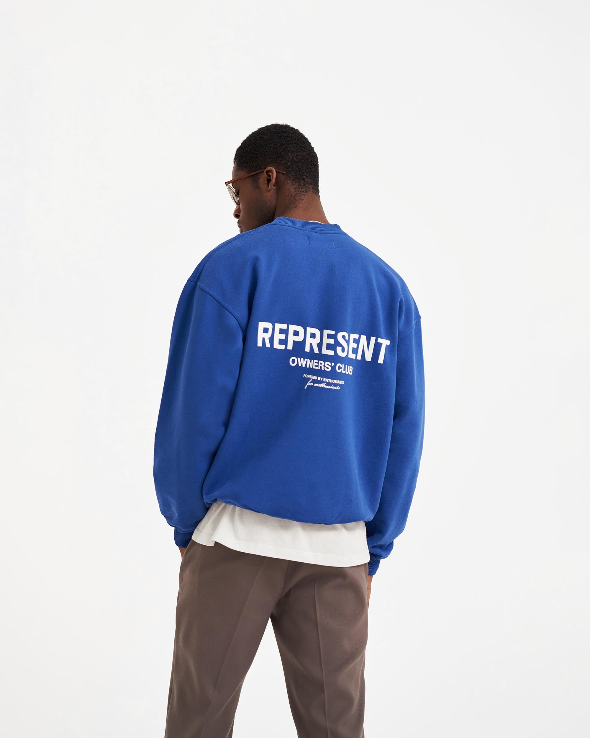 Man wearing an oversized blue sweater on a plain white background | Represent Owners Club Sweater in Cobalt | Heavy weight jersey cotton sweater with ribbed trims | Owners Club Sweaters | Represent Clo